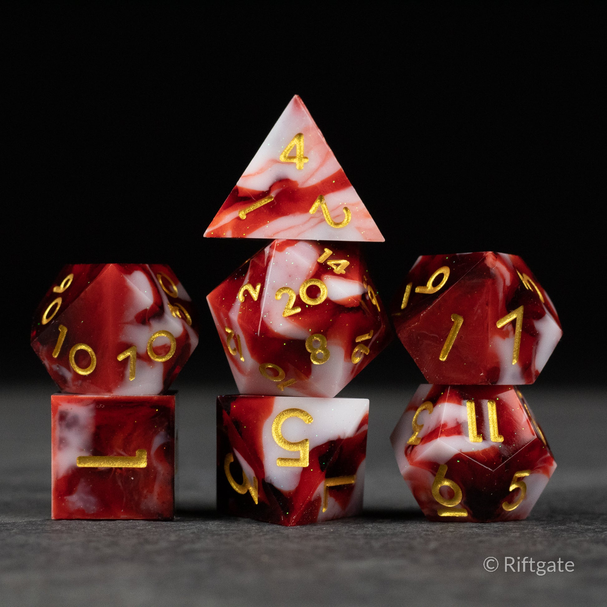 Blood and Snow Dice Set - Seven-piece sharp-edged dice set in red and white marbled design with gold numbers.
