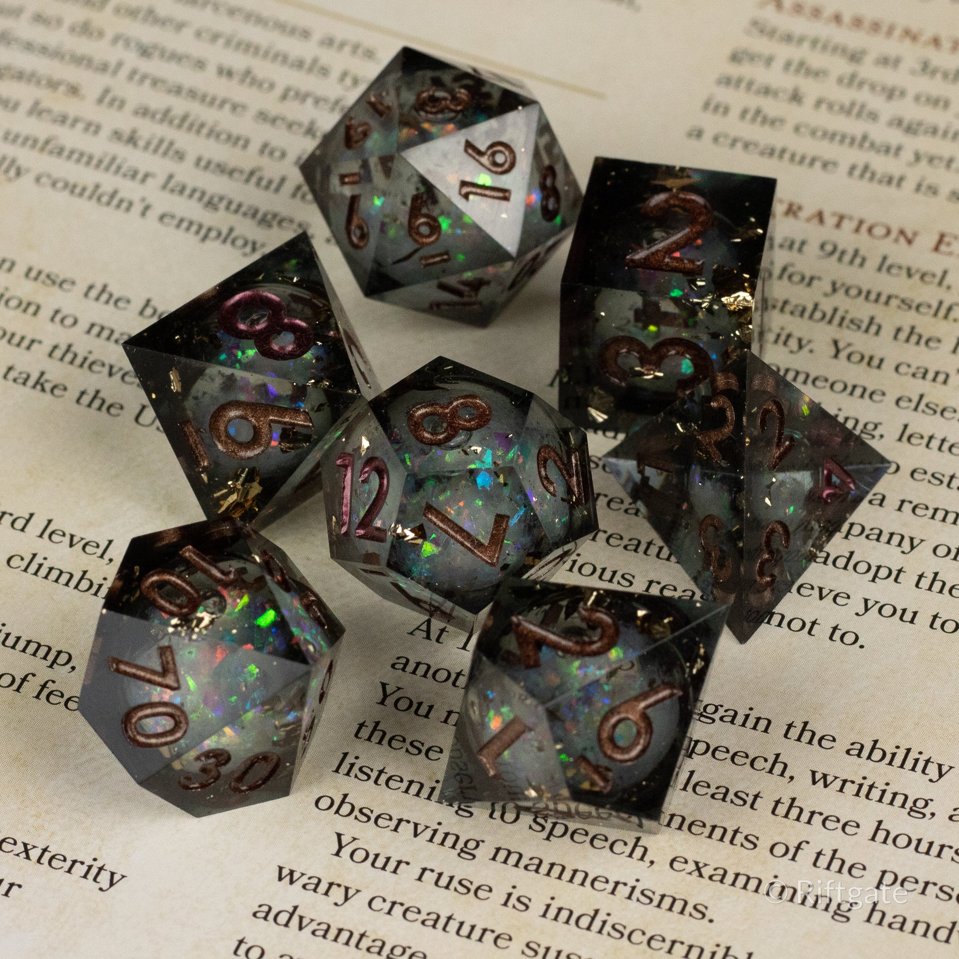 Wild Magic Liquid Core Dice Set - Set of seven sharp-edged polyhedral dice with translucent black and smoky gray liquid cores and iridescent colorful flecks.