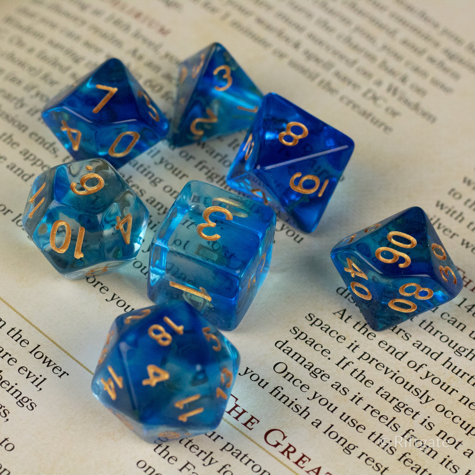 Ethereal Mist Dice Set - Set of nine translucent blue polyhedral dice with gold numbers, featuring varying shapes including d20, d12, d10, d8, d6,.