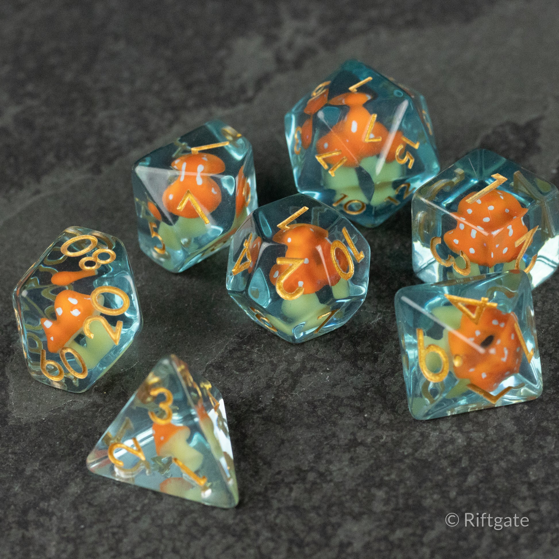 Orange + Blue Resin Mushroom Dice Set - Set of translucent blue resin dice with bright orange mushroom inclusions and gold numbering.