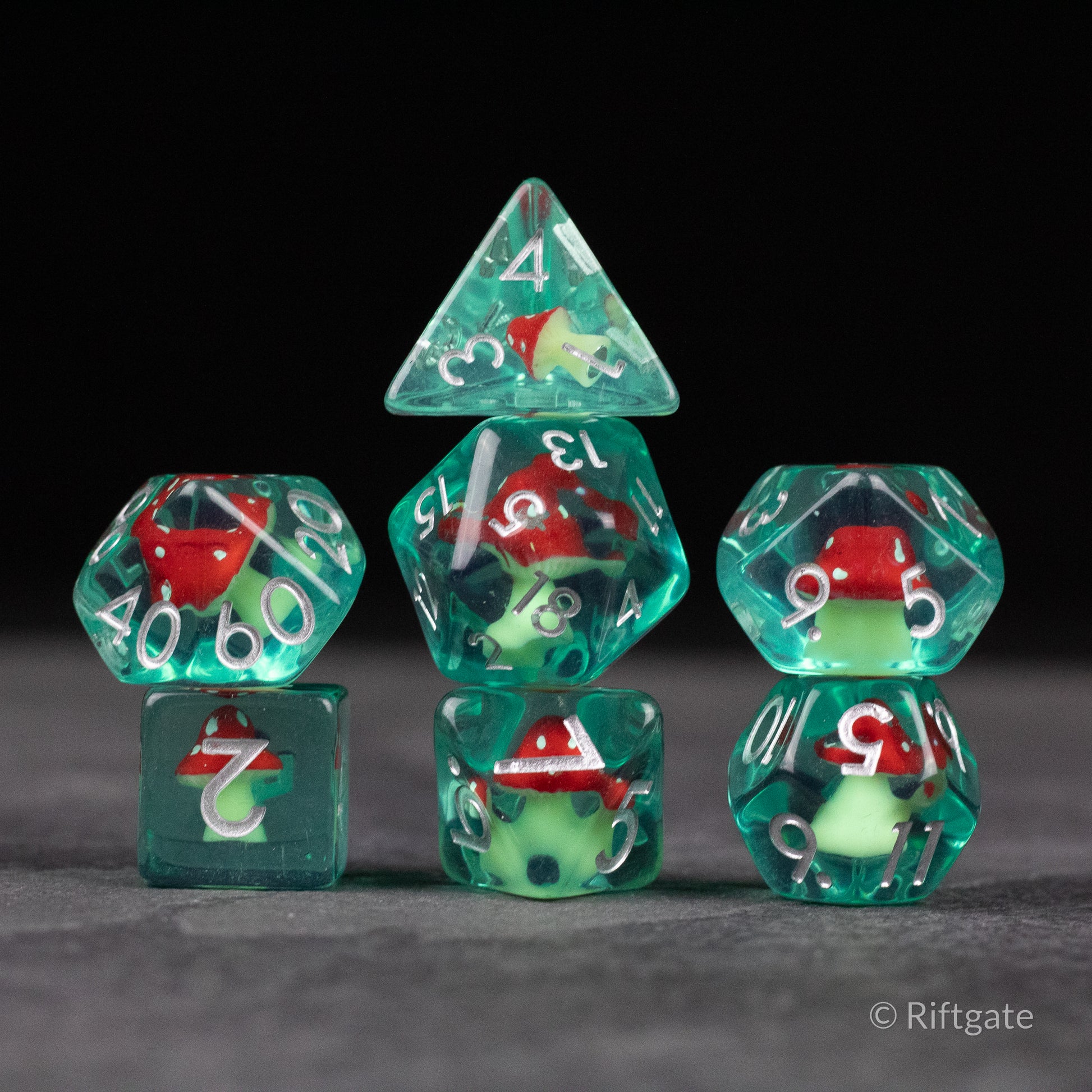 Red + Green Resin Mushroom Dice Set - Set of seven translucent resin dice with red and green mushroom-shaped inclusions and white numbering.