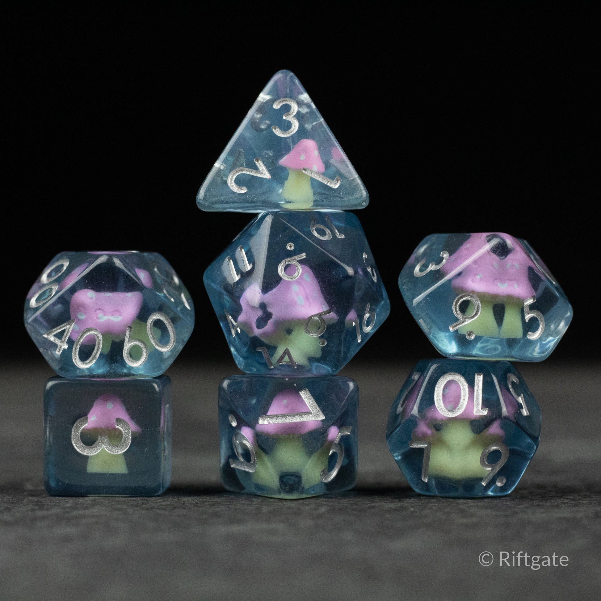 Pink + Blue Resin Mushroom Dice Set - Set of translucent blue and pink resin dice with embedded miniature pink mushroom inclusions, featuring various polyhedral.