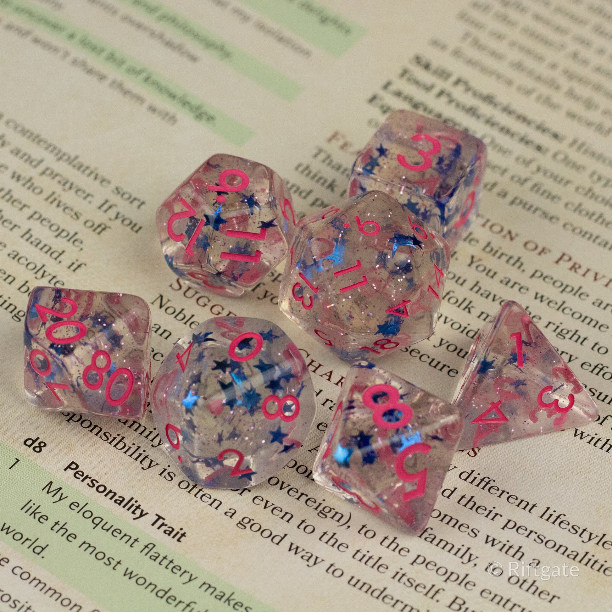 Blue Star Pink Glitter Dice - Transparent pink glitter dice set with blue numbers and star-shaped inclusions on a book background.