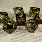 Ambershadow Dice Set - Amber-hued translucent polyhedral dice set with gold numbering and smoky inclusions.