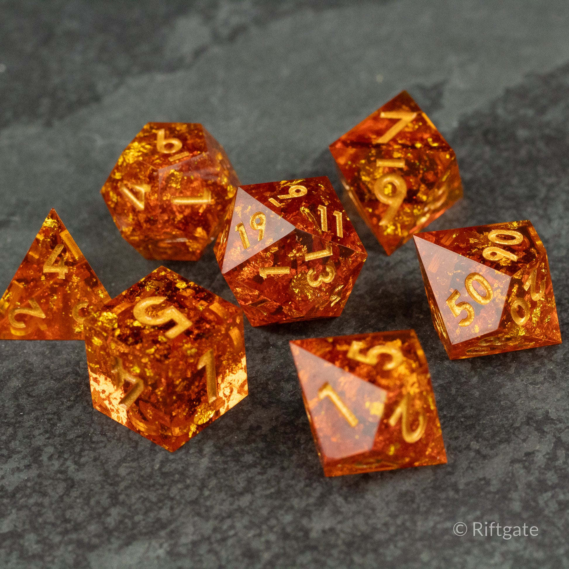 Sunforged Dice Set - Transparent amber-orange polyhedral dice set with gold numbers and sharp edges on a dark textured surface.