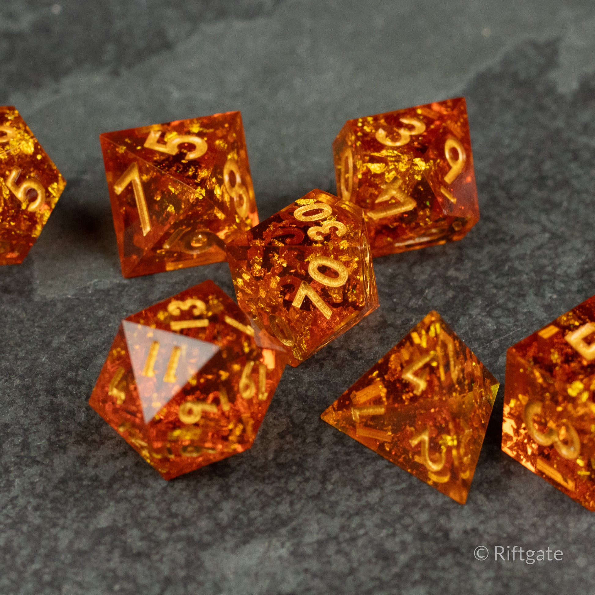Sunforged Dice Set - Amber-orange translucent polyhedral dice set with sharp edges and golden numbers on a dark textured surface.