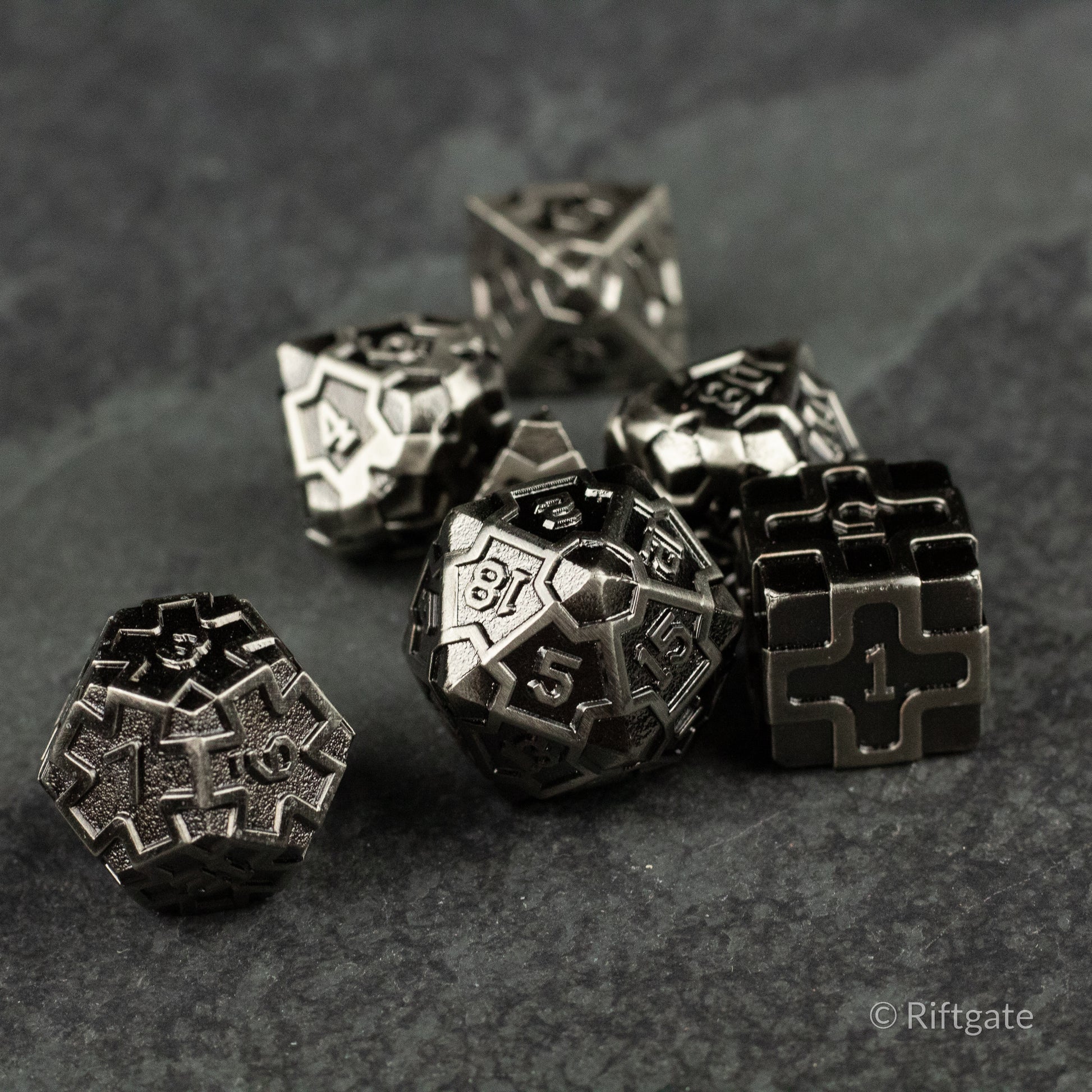 Iron Crusader - Set of black metal polyhedral dice with silver engraved numbers and intricate geometric details.