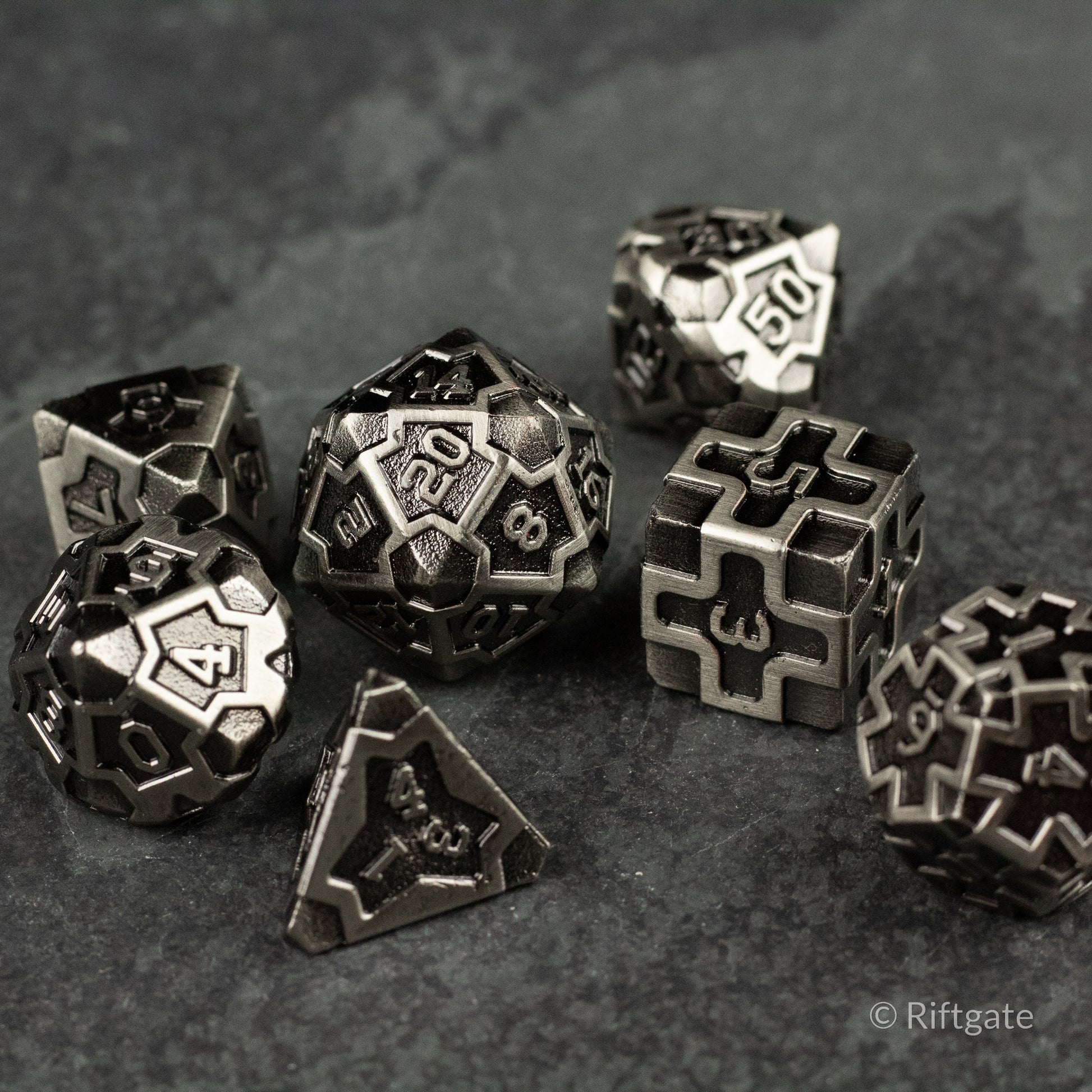 Iron Crusader - Set of black and silver metal gaming dice with intricate geometric and numeral engravings, including d4, d6, d8, d10, d12,.