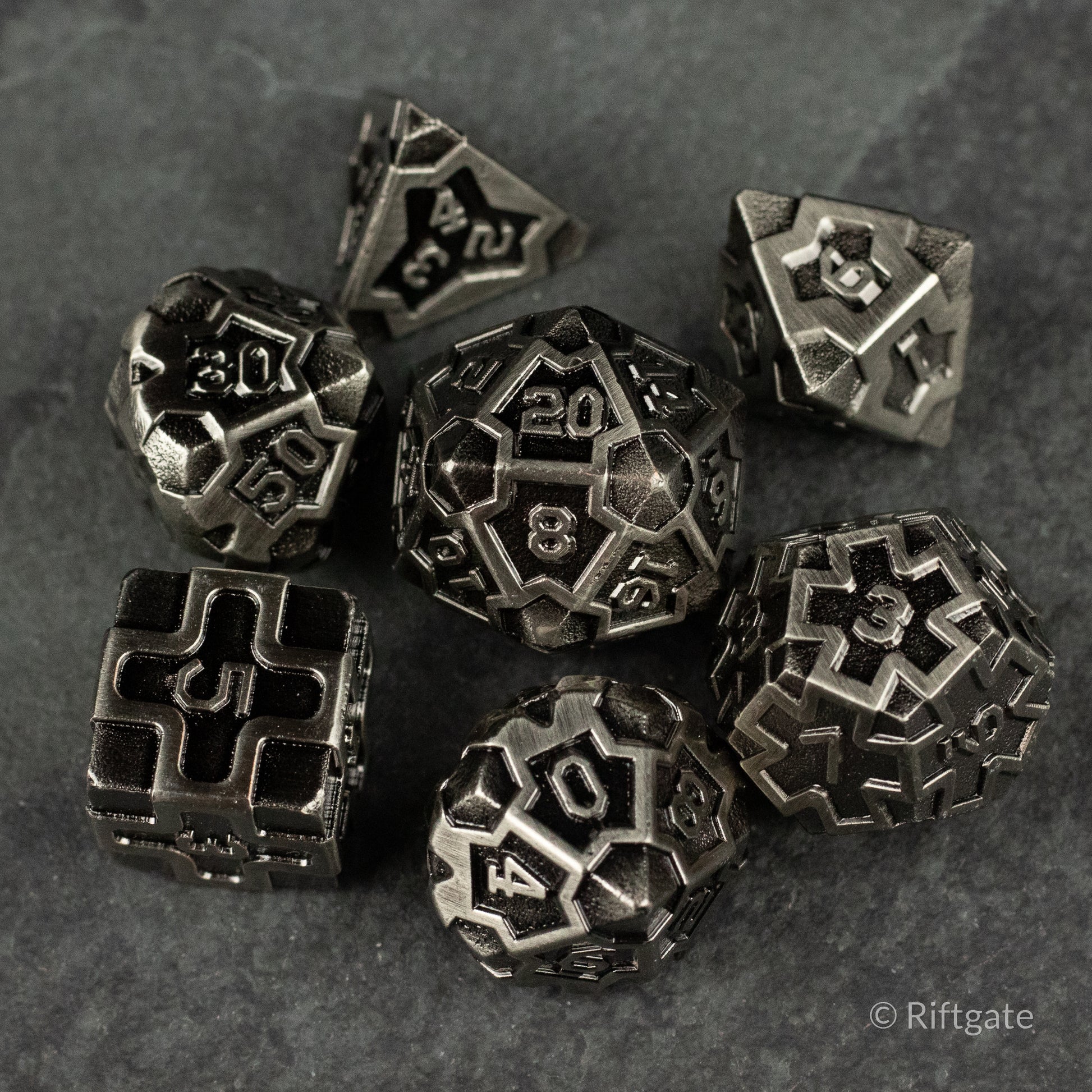Iron Crusader - Set of seven metal polyhedral dice with an intricate iron cross design on each face and a dark, weathered finish.