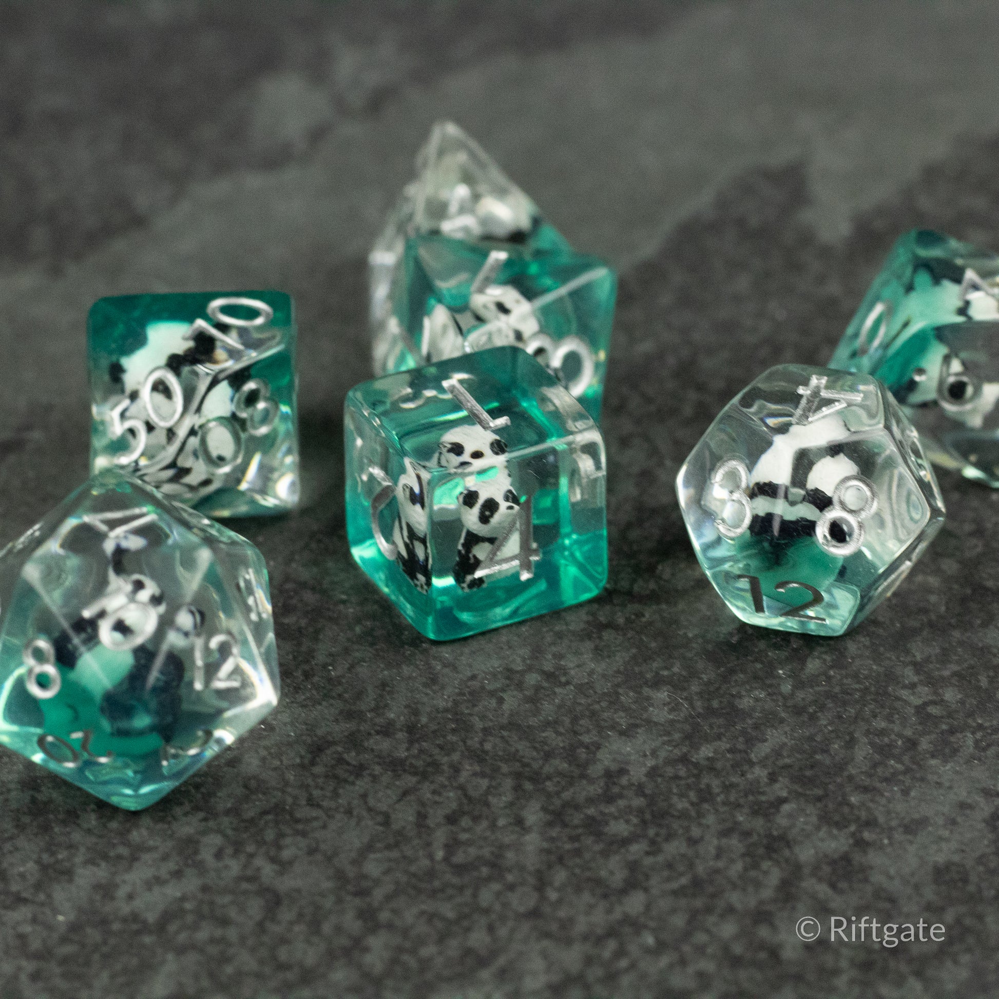 Panda Dice Set - Translucent teal polyhedral dice set with white numbers and black panda faces inside.
