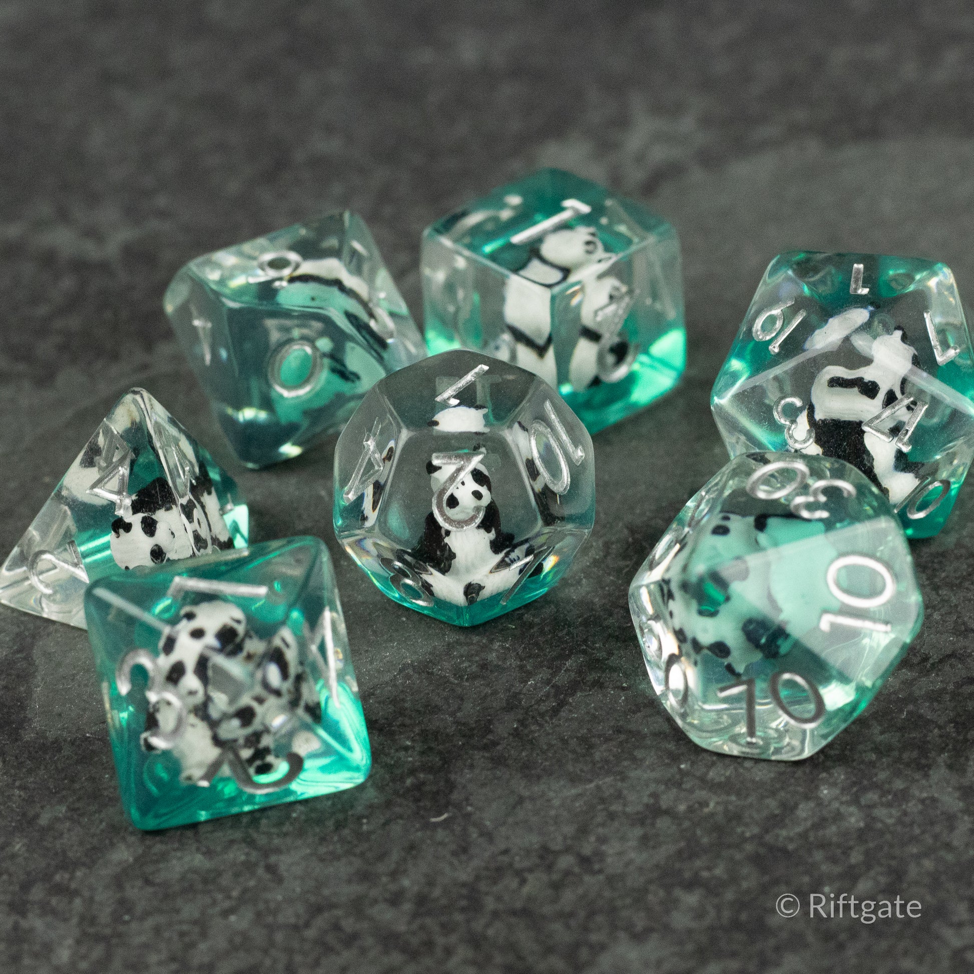 Panda Dice Set - Set of seven translucent teal polyhedral dice with embedded small panda figurines and white numbering.