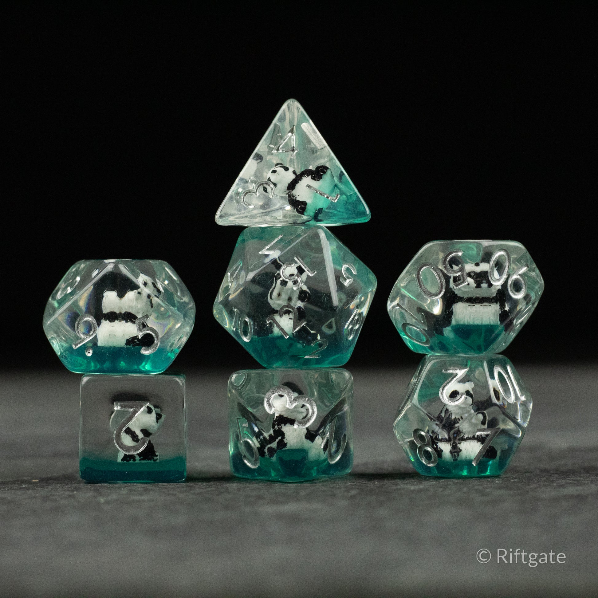 Panda Dice Set - Set of seven clear turquoise polyhedral dice with suspended black and white panda figures inside each die.