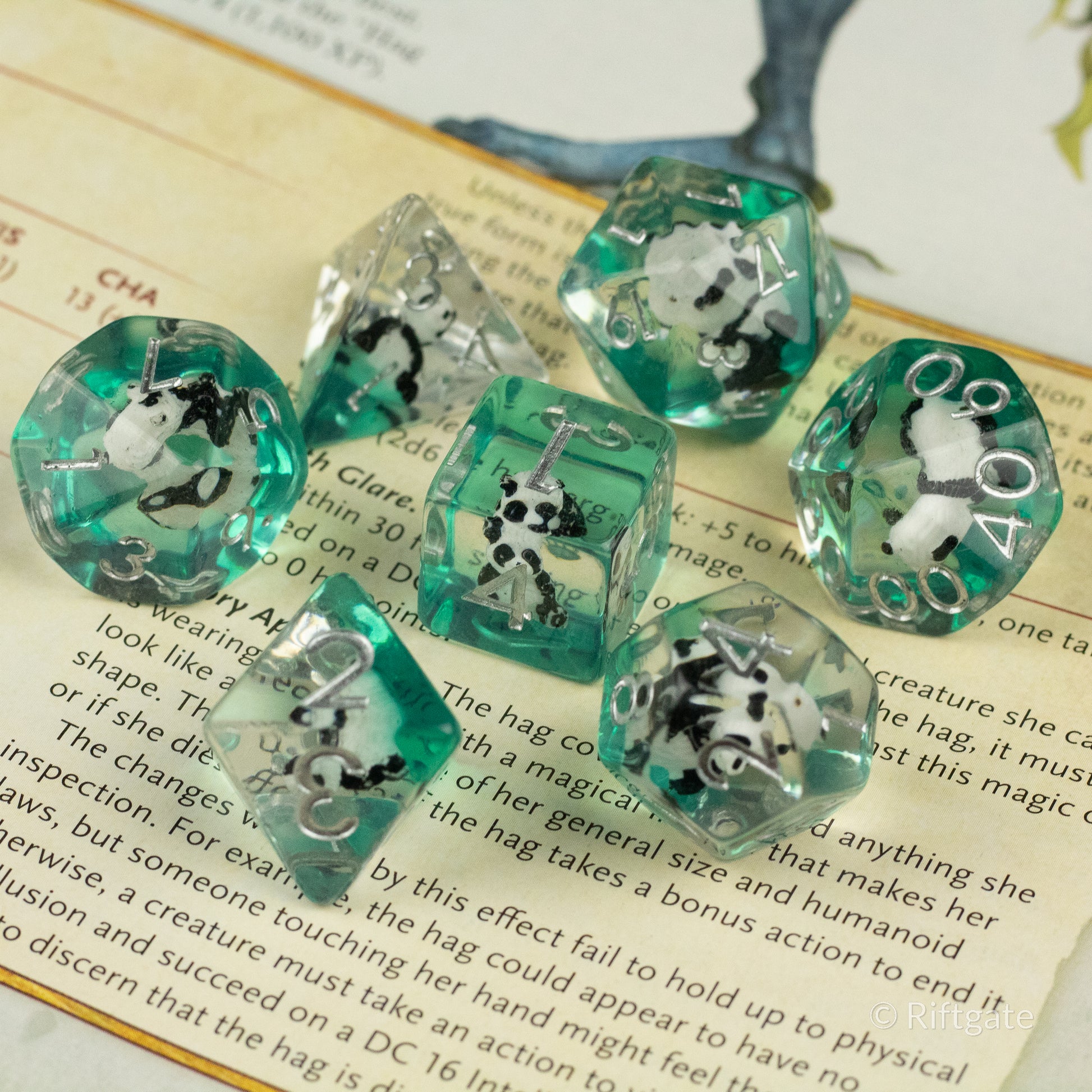 Panda Dice Set - Set of seven translucent green and clear polyhedral dice with black-and-white panda inclusions inside each die.