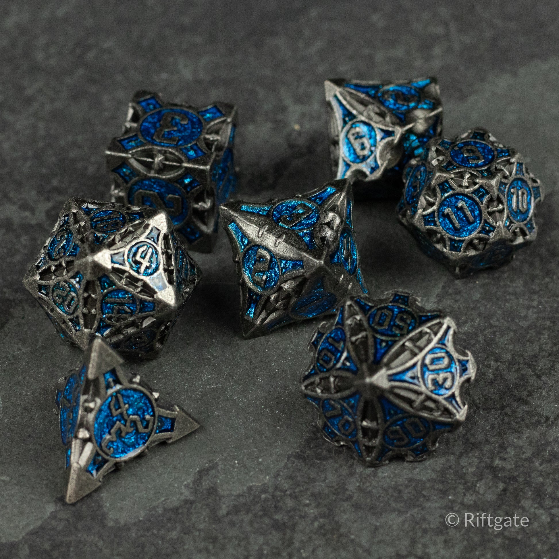 Gray Empyrean Artifact Dice Set - Gray metal dice set with intricate blue inlays featuring various geometric shapes and multiple facets.