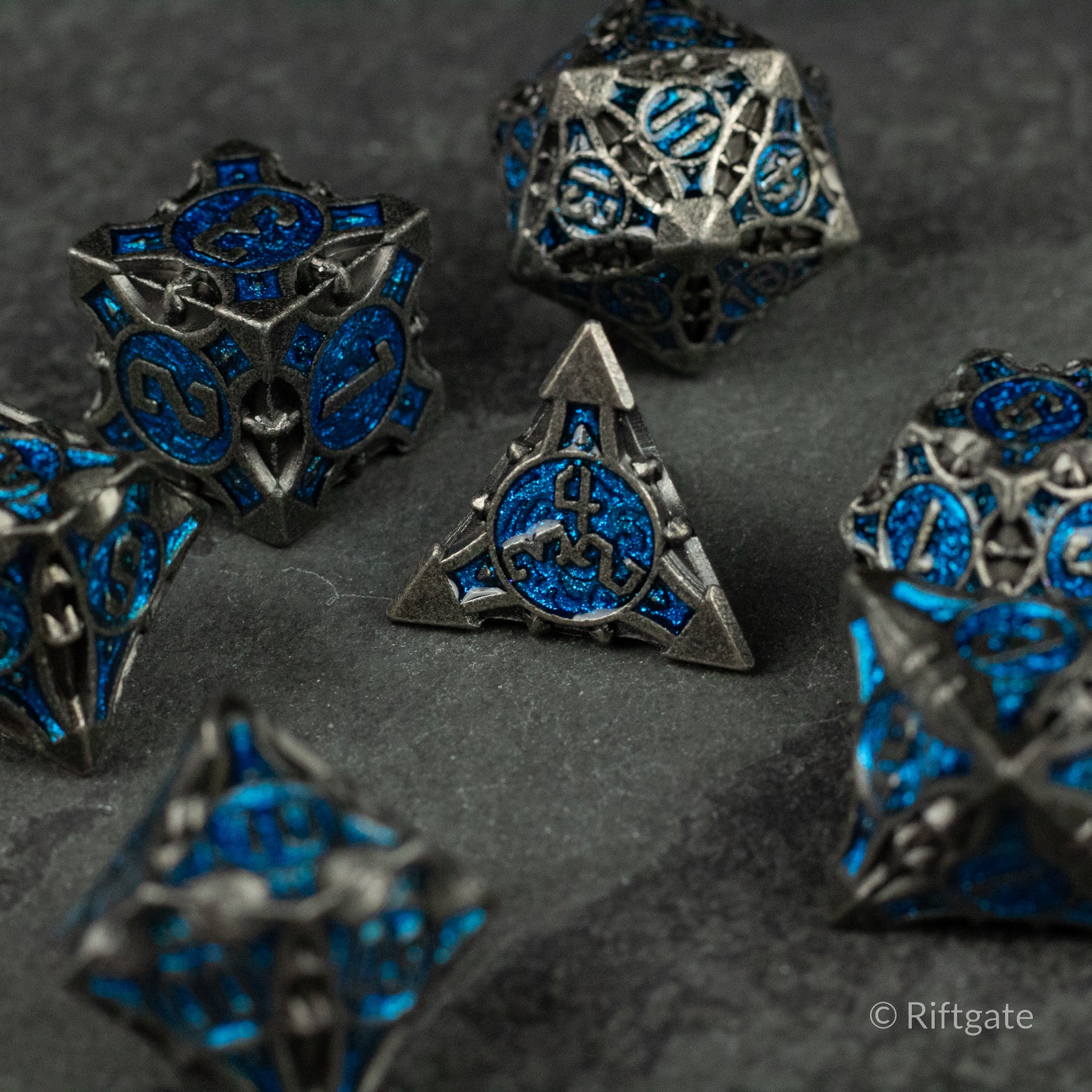 Gray Empyrean Artifact Dice Set - Gray metallic polyhedral dice set with intricate blue engravings and ornate designs.