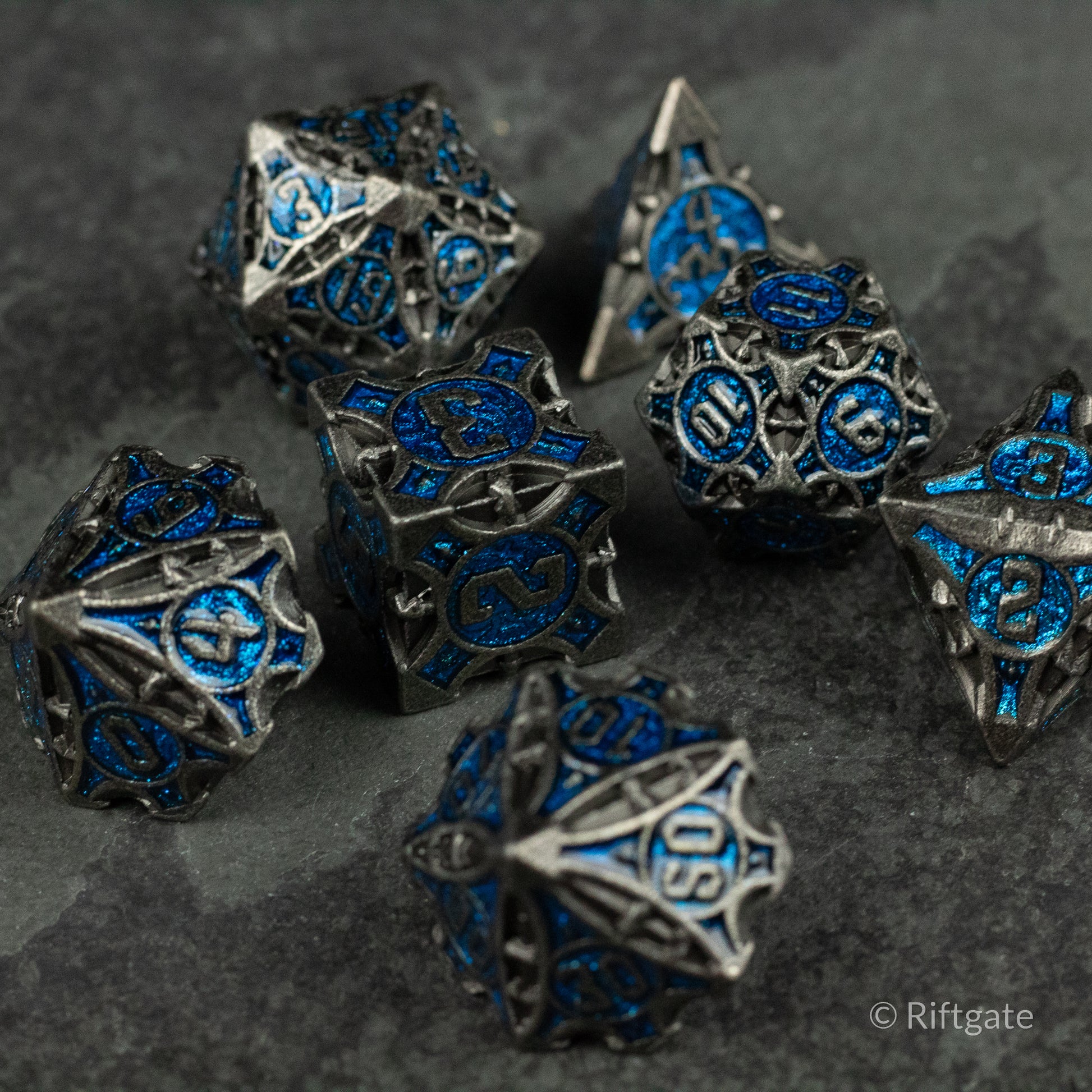 Gray Empyrean Artifact Dice Set - Gray metal polyhedral dice set with intricate blue engravings on each face.