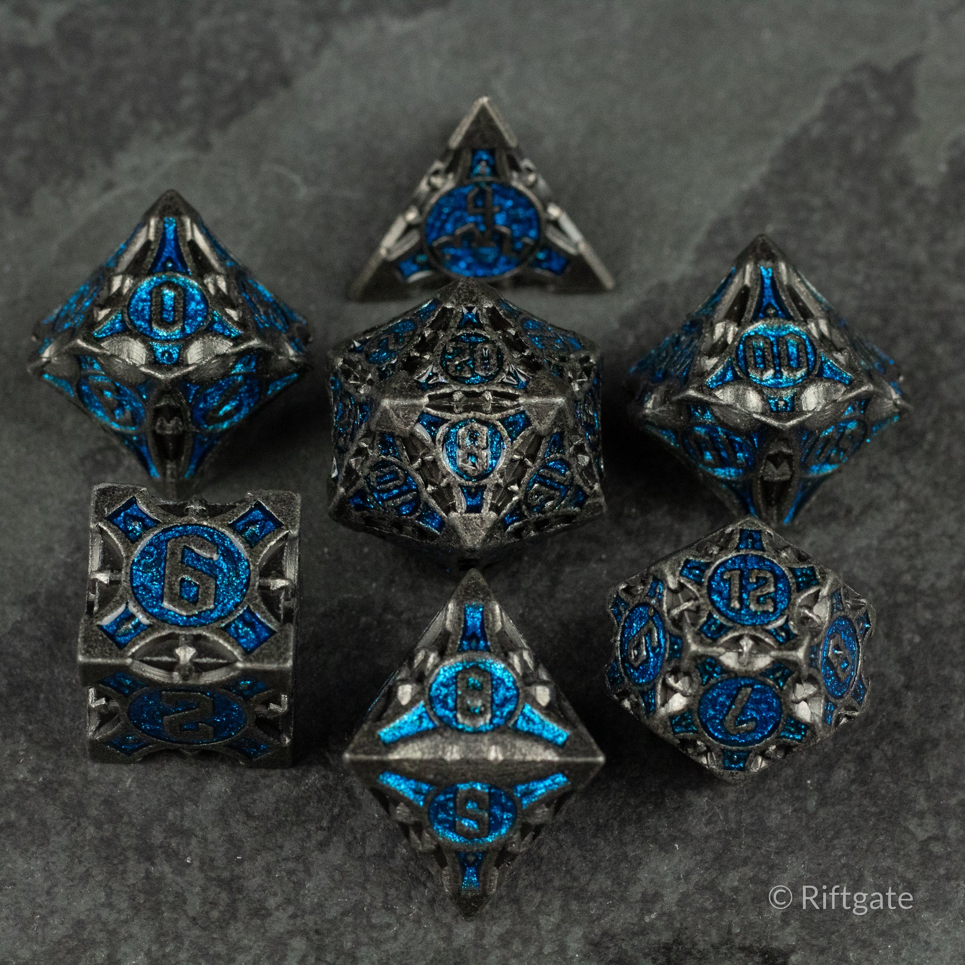 Gray Empyrean Artifact Dice Set - Gray metal polyhedral dice set with intricate blue enamel details and ornate engravings.
