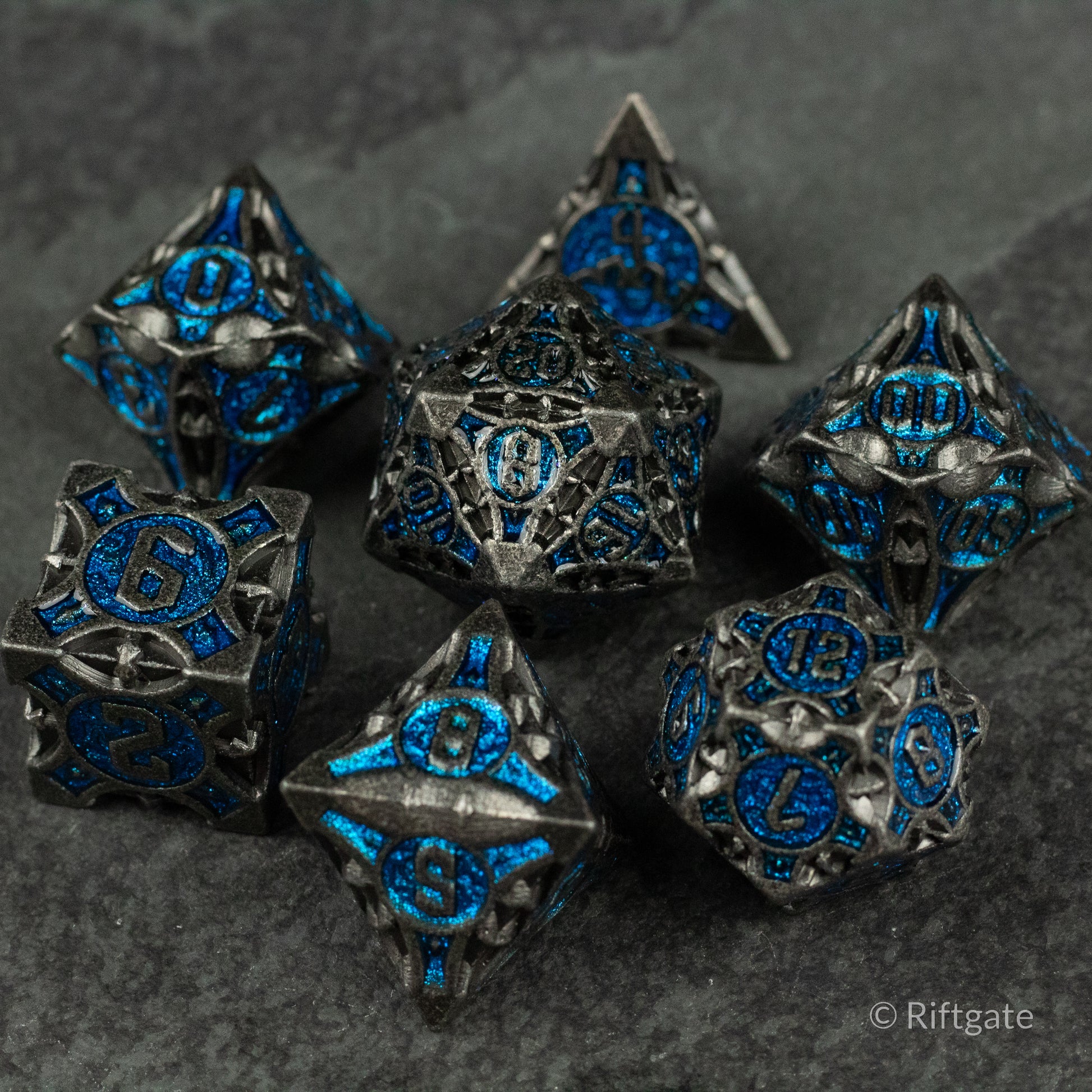 Gray Empyrean Artifact Dice Set - Gray metal polyhedral dice set with intricate blue glowing numbers and ornate detailing.