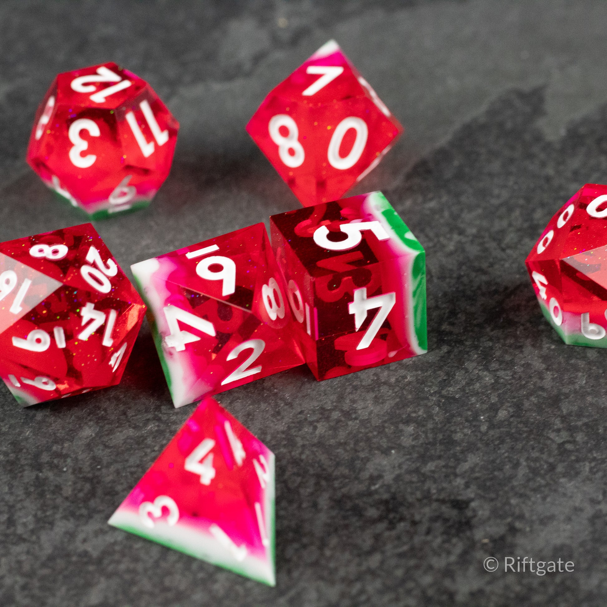 Watermelon Sharp Edge Dice - Set of translucent red sharp edge polyhedral dice with white numbers and green-and-white watermelon-rind pattern on one die.