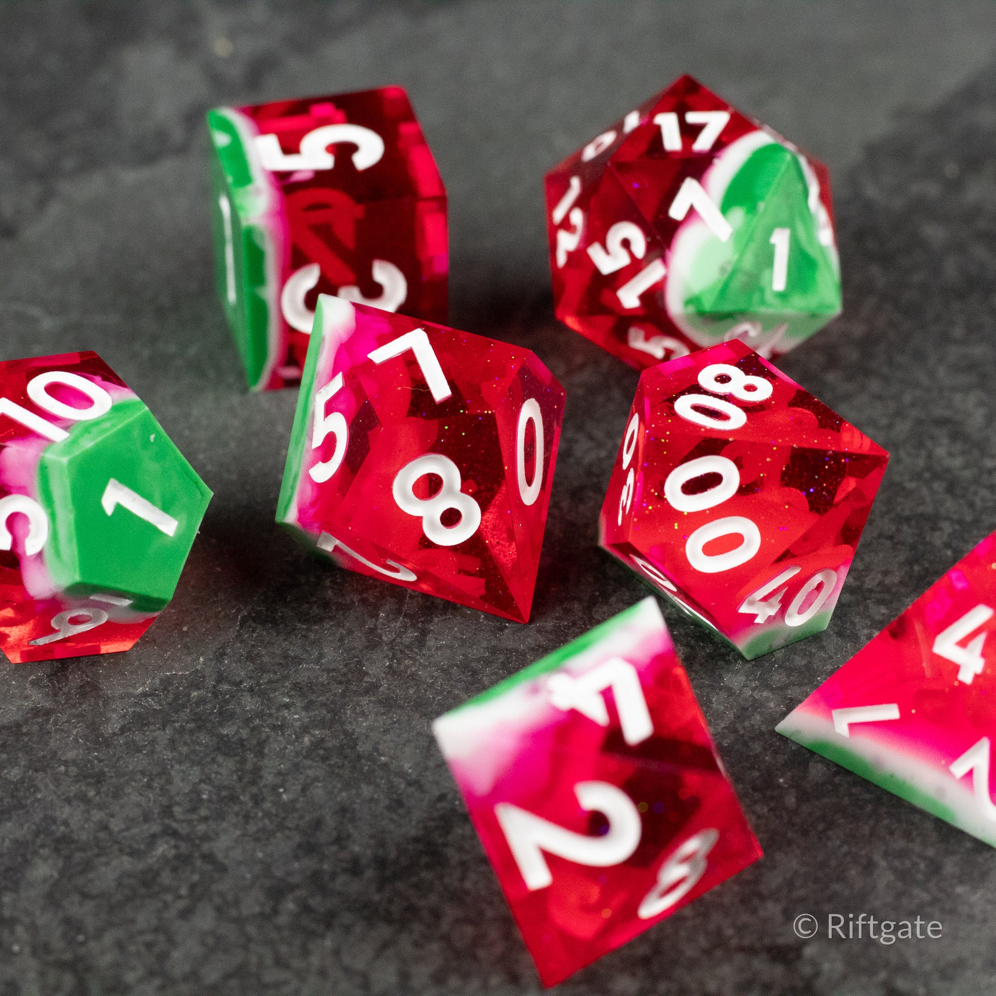Watermelon Sharp Edge Dice - Set of seven polyhedral dice with sharp edges in translucent red and green resembling watermelon colors, white numbers.
