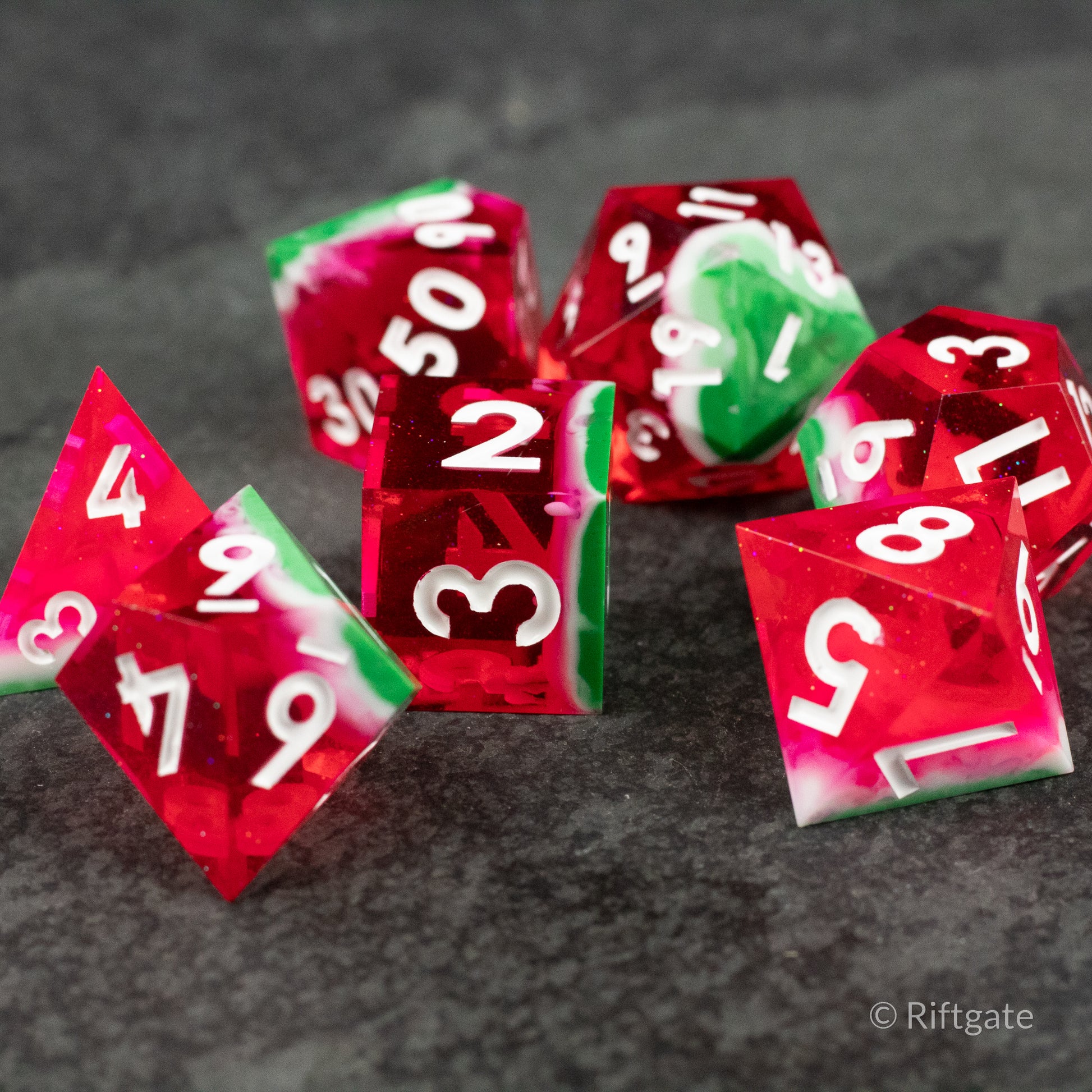 Watermelon Sharp Edge Dice - Set of translucent red and green sharp-edged polyhedral dice with white numbers, resembling watermelon colors.