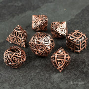 Runeweave Metal Dice Set - Copper-colored metal dice set with intricate rune-like engravings and various polyhedral shapes.