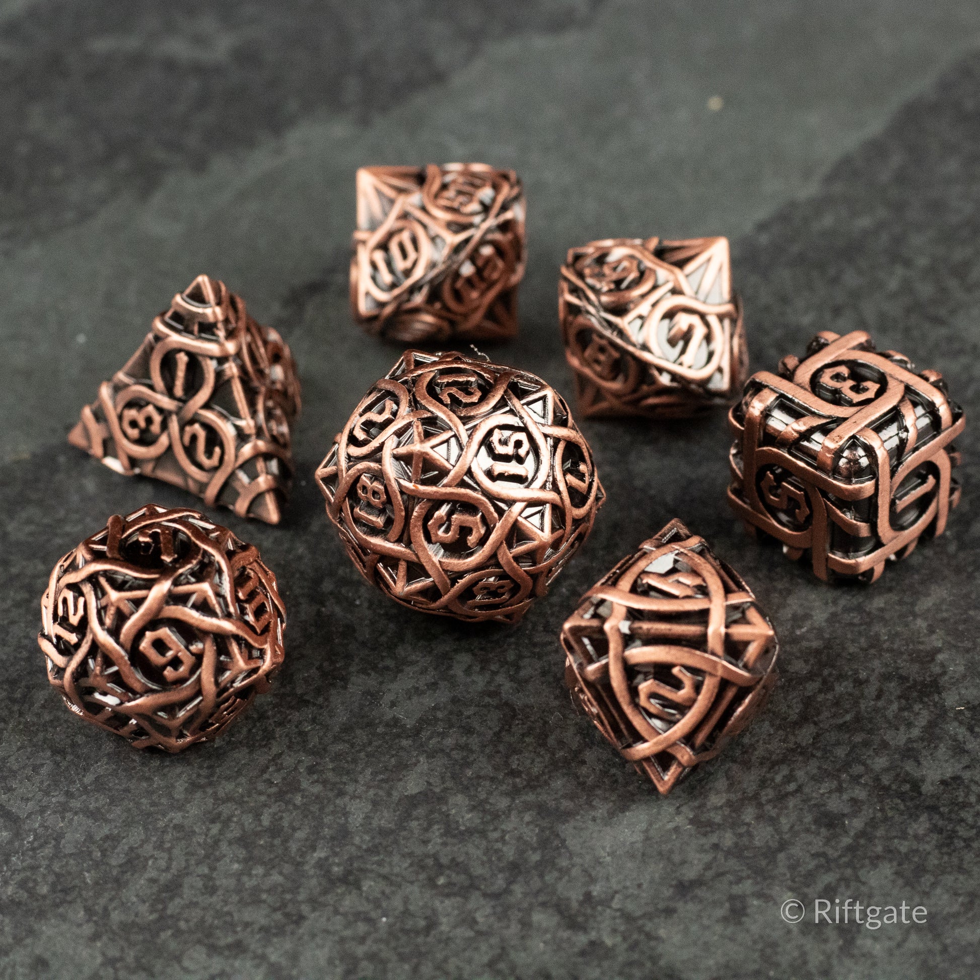 Runeweave Metal Dice Set - Copper-colored metal dice set with intricate rune-like engravings and various polyhedral shapes.