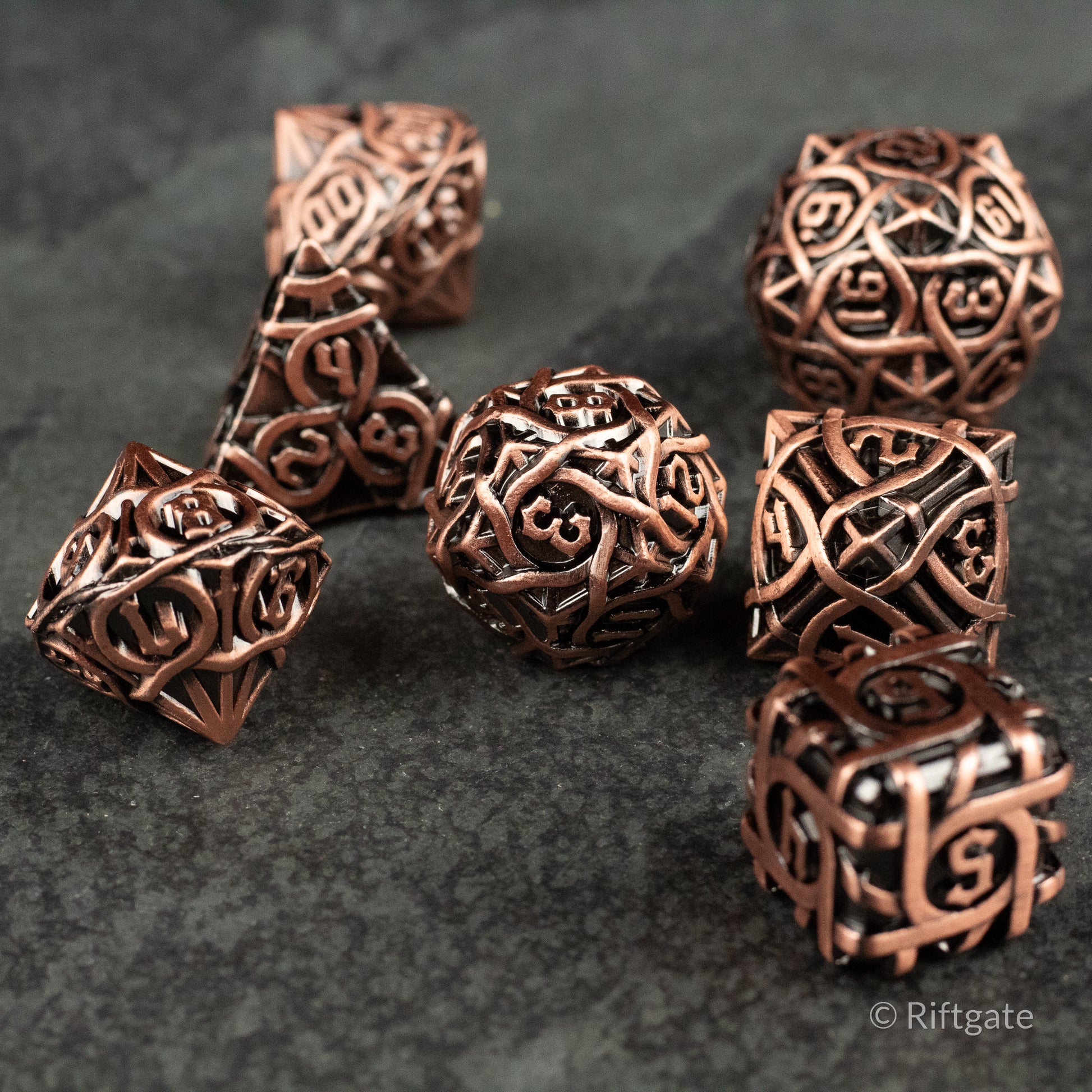 Runeweave Metal Dice Set - Copper-colored metal dice set with intricate Celtic knot and rune engravings on various polyhedral shapes.