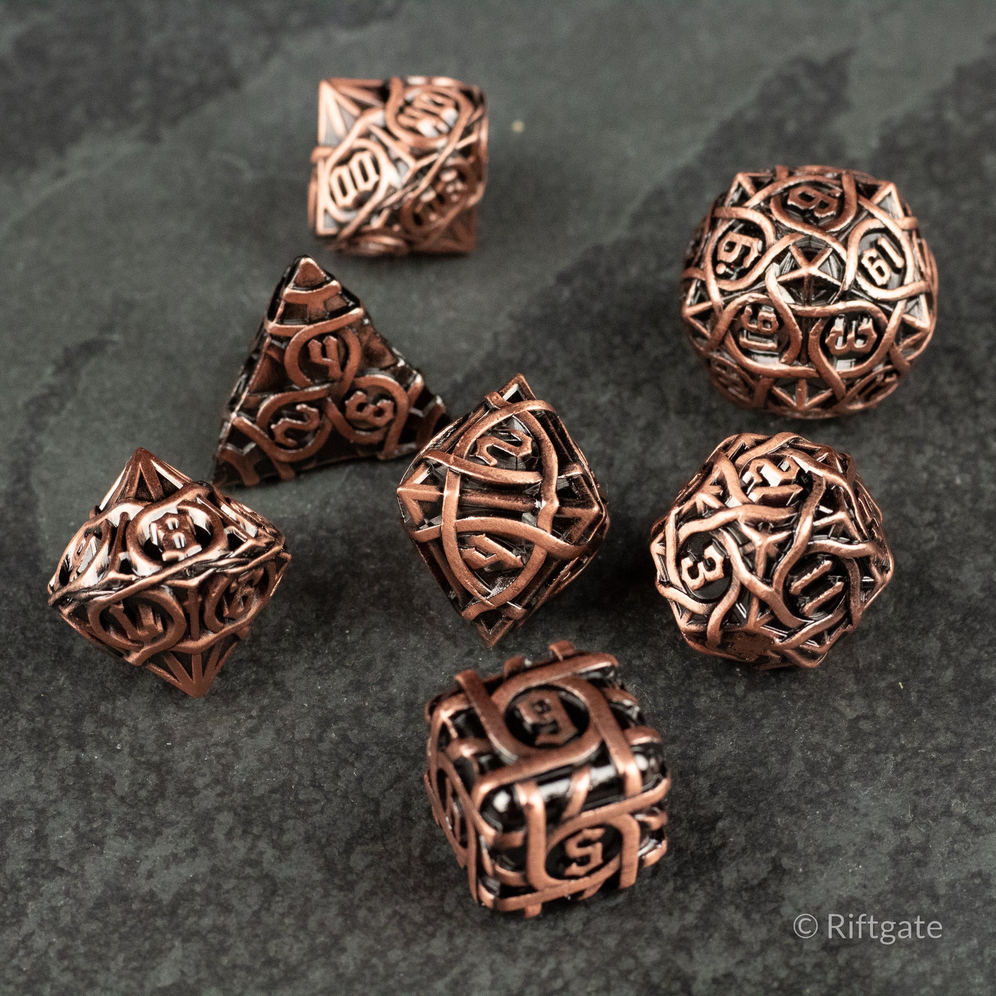 Runeweave Metal Dice Set - Copper-colored metal dice set with intricate rune-like engravings, including d4, d6, d8, d10, d12, d20, and percentile dice.