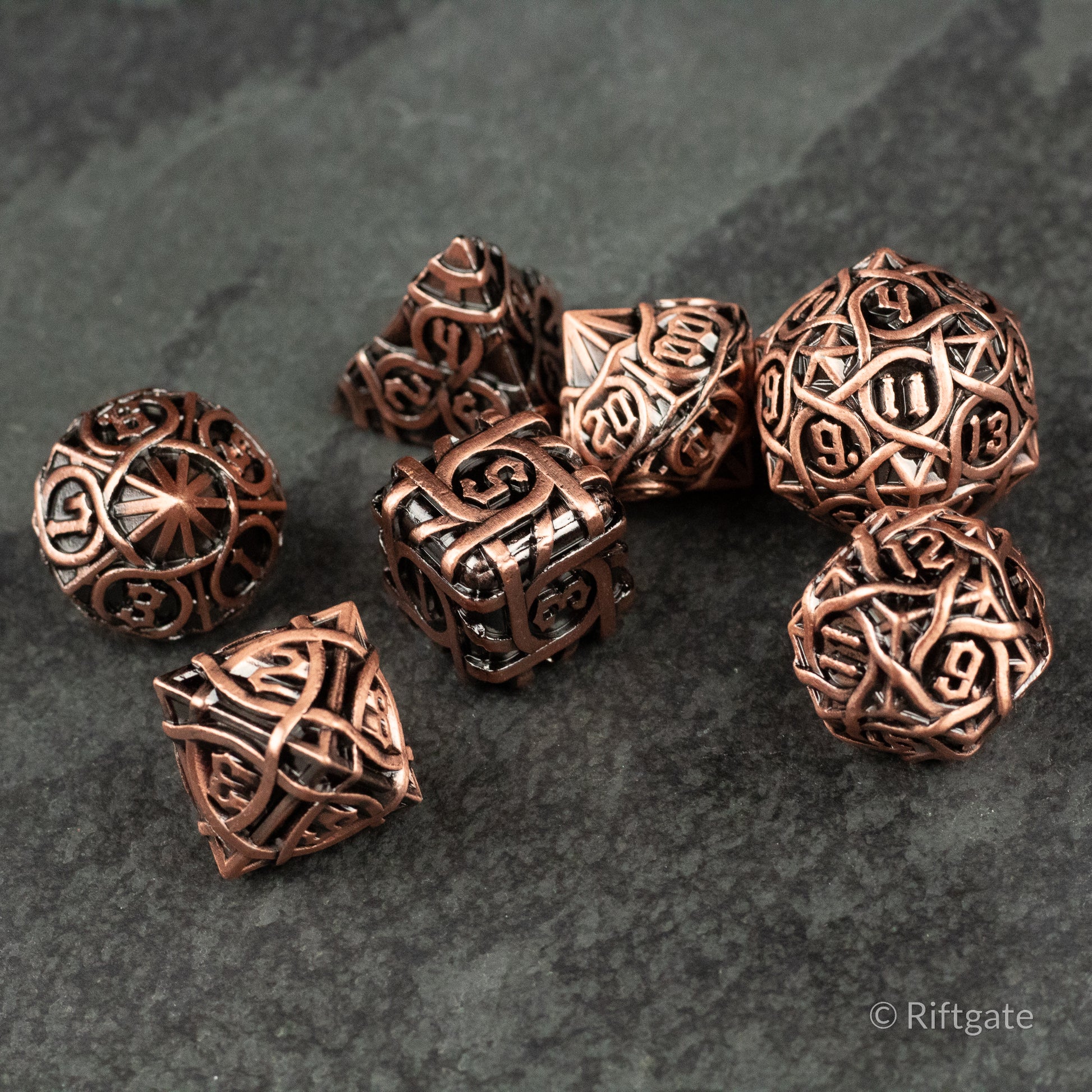 Runeweave Metal Dice Set - Seven copper-colored metal polyhedral dice with intricate rune-style engravings on a dark textured surface.