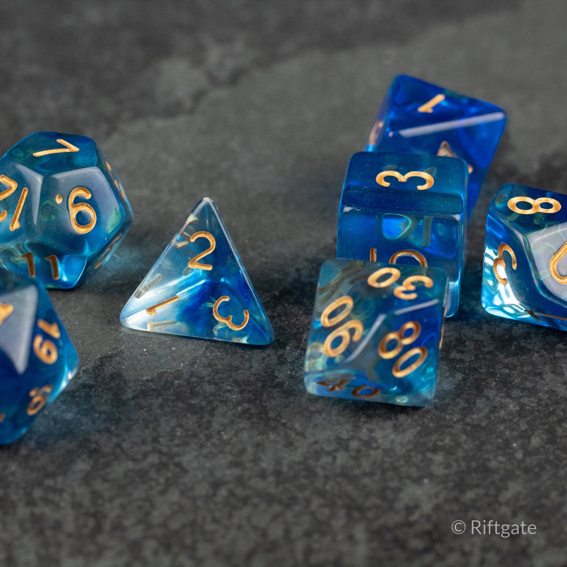 Ethereal Mist Dice Set - Seven blue translucent polyhedral dice with gold numbers, including d4, d6, d8, d10, d12, and d20 shapes.