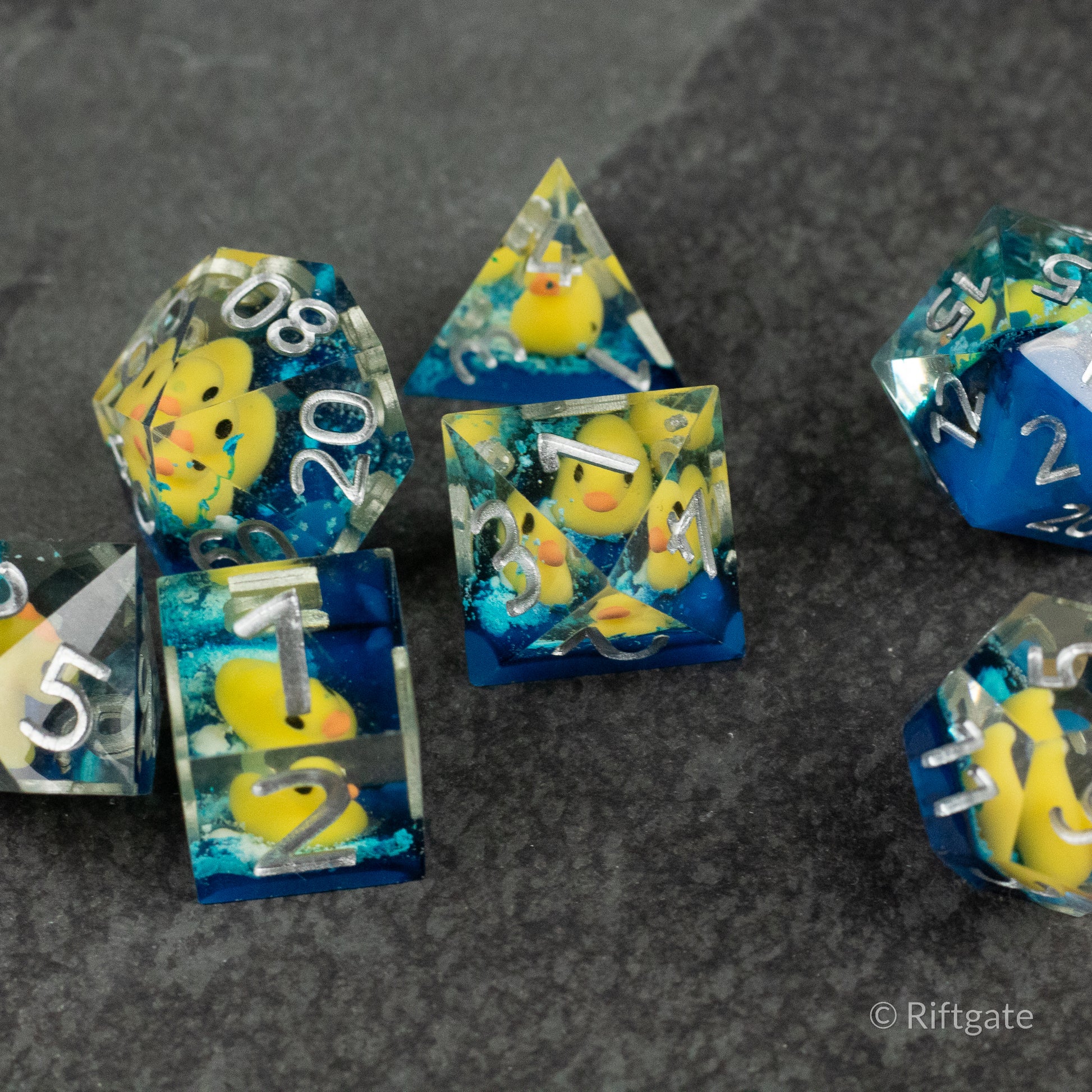 Rubber Duck Sharp Edge Dice - Set of sharp-edge polyhedral dice with clear resin and embedded yellow rubber ducks and blue swirls, including d20, d12, d8,