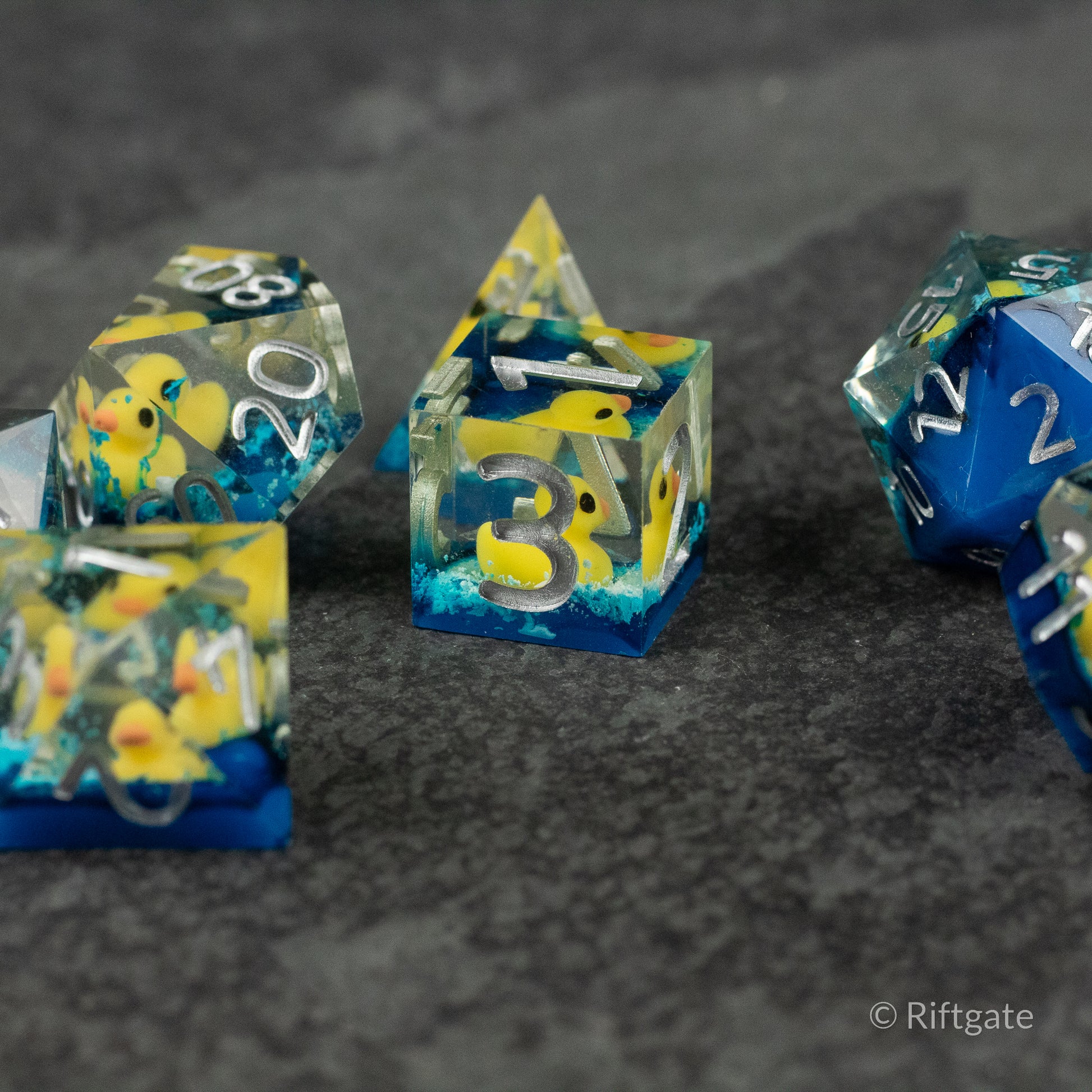 Rubber Duck Sharp Edge Dice - Clear resin sharp edge dice with yellow rubber duck inclusions and white numbering.