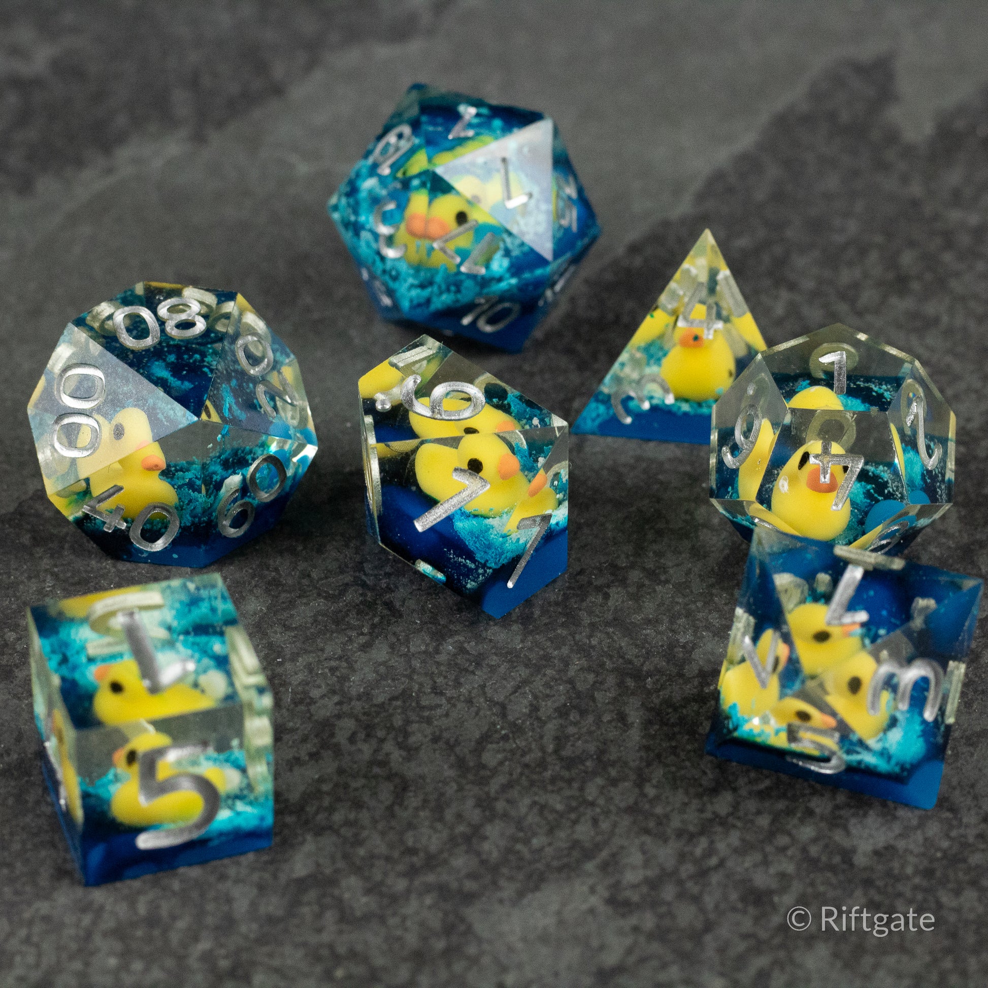 Rubber Duck Sharp Edge Dice - Set of clear blue sharp-edged polyhedral dice with embedded yellow rubber ducks and white numbering.