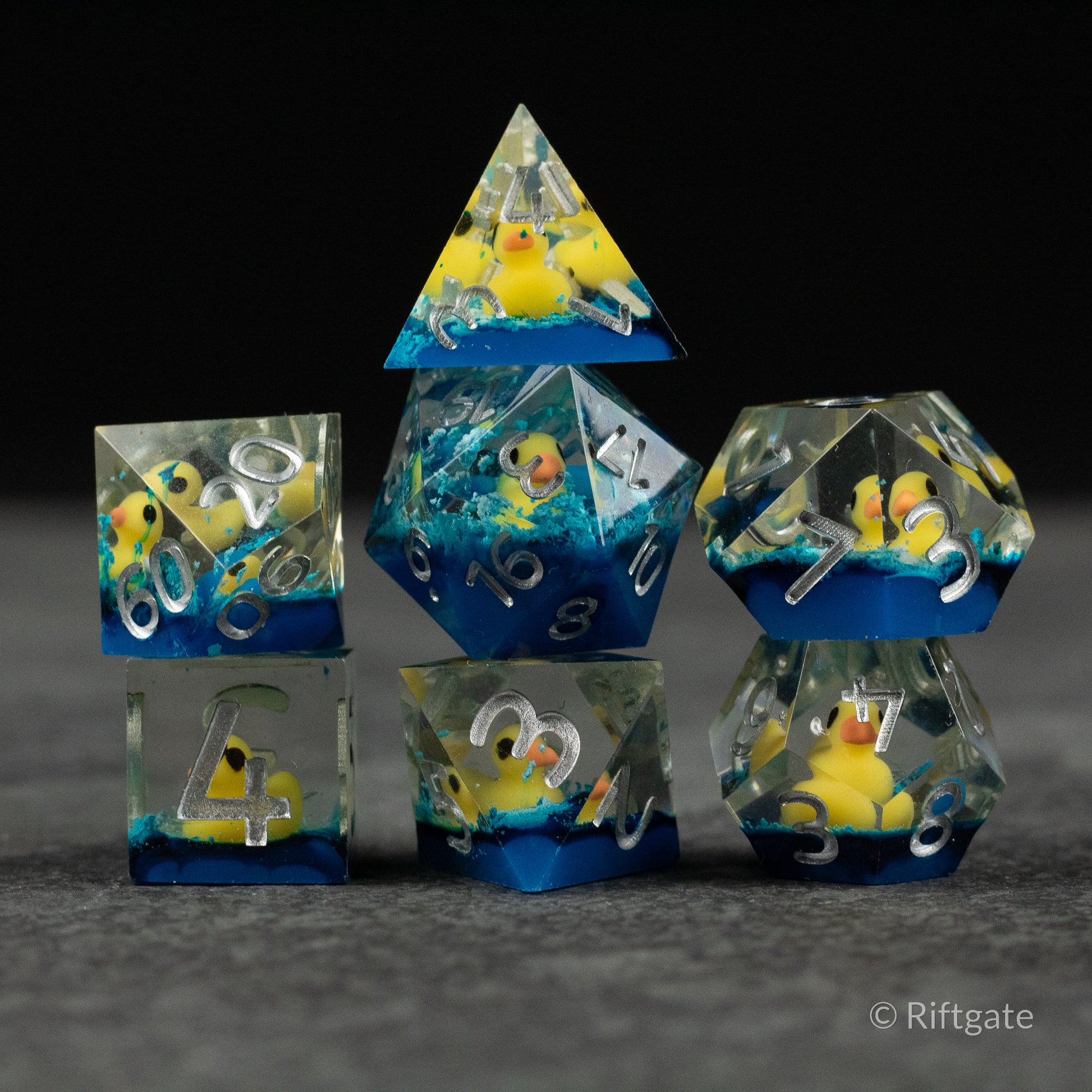 Rubber Duck Sharp Edge Dice - Set of clear resin polyhedral dice with sharp edges, each containing a small yellow rubber duck submerged in blue liquid.