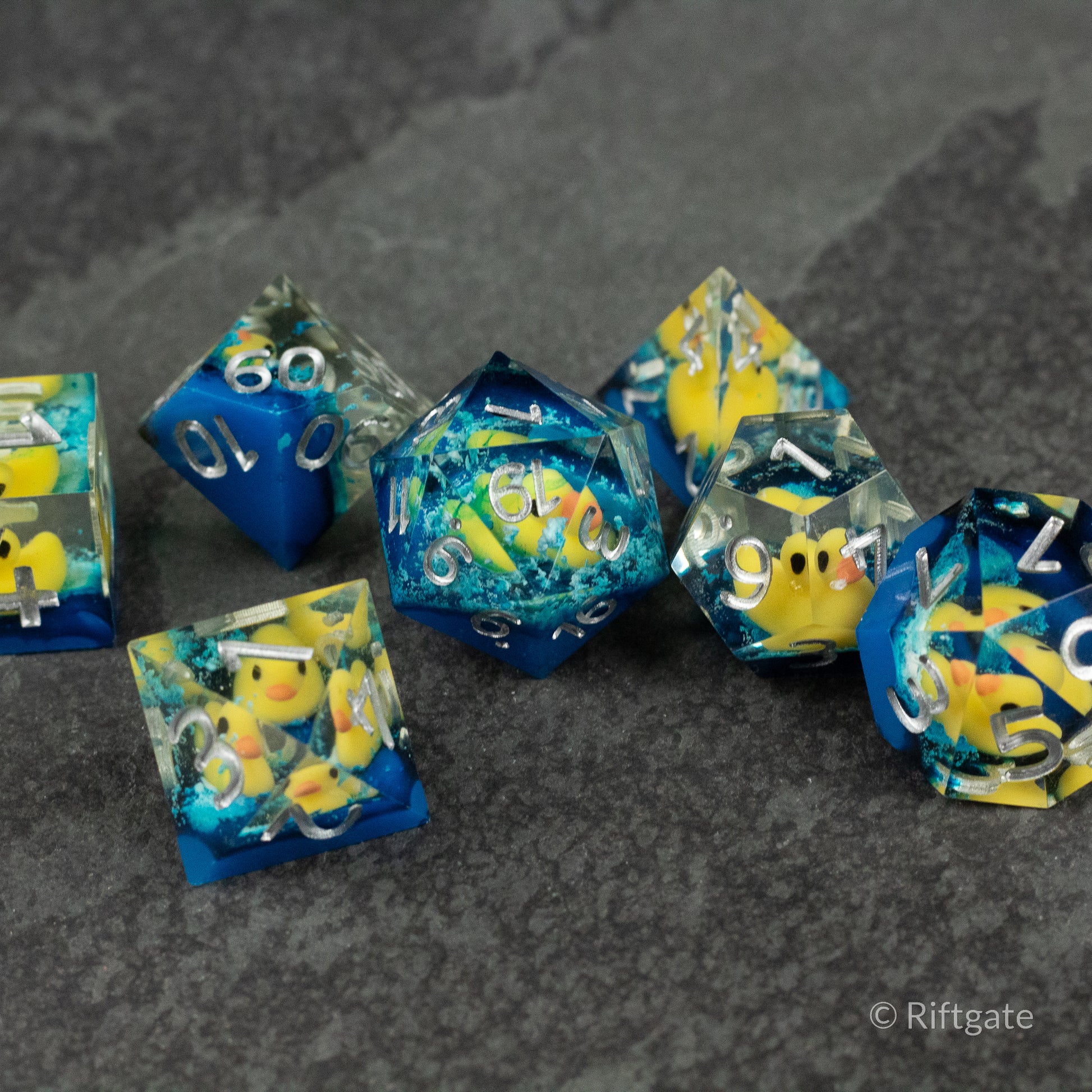 Rubber Duck Sharp Edge Dice - Set of sharp-edged polyhedral dice with blue and yellow swirls and embedded rubber duck figures.