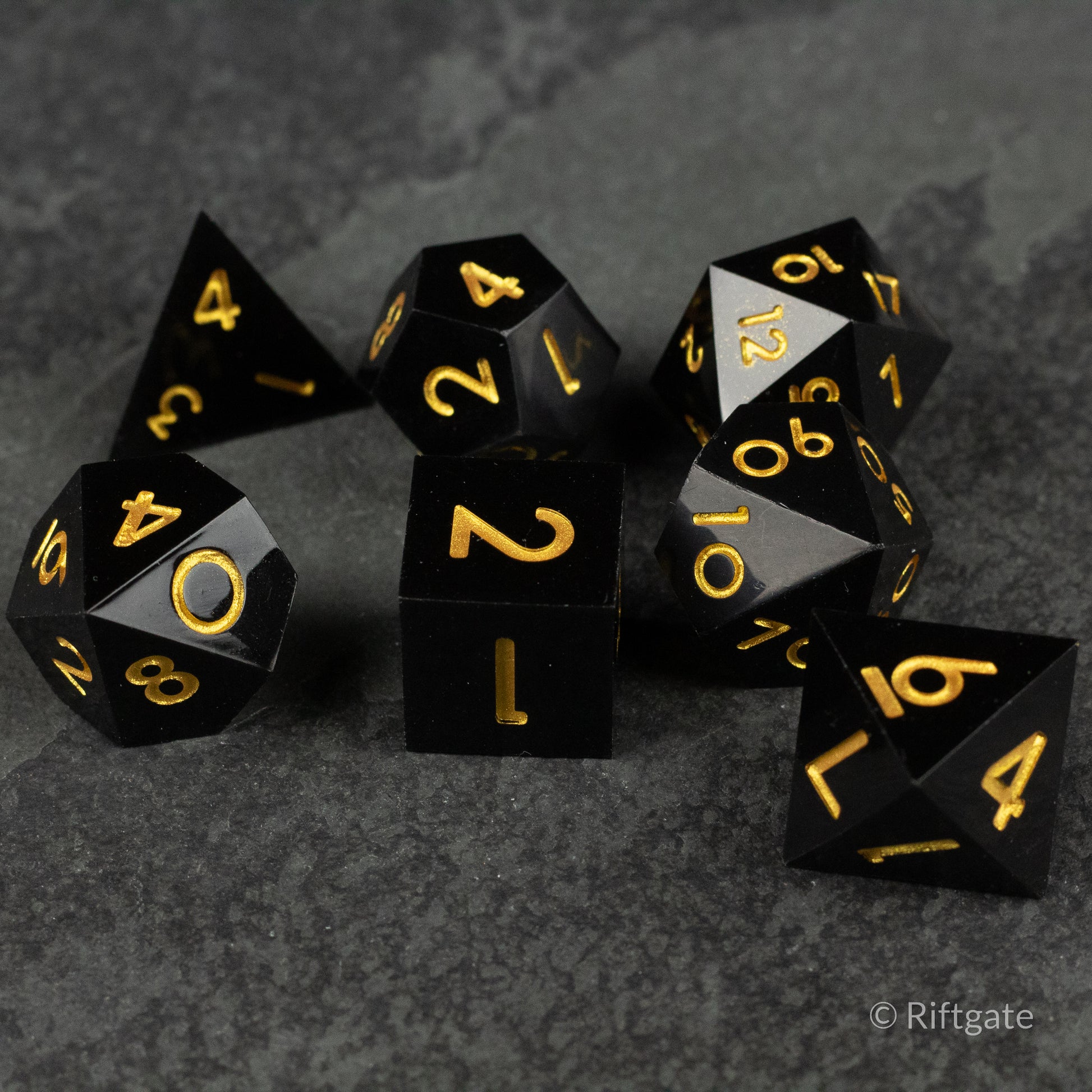 Midnight Sovereign Dice Set - Black sharp-edged polyhedral dice set with gold numbering on a dark textured surface.