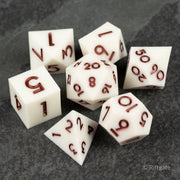 Glacial Spark Dice Set - Seven white polyhedral dice with sharp edges and red metallic numbers, including d4, d6, d8, d10, d12, and d20 designs.