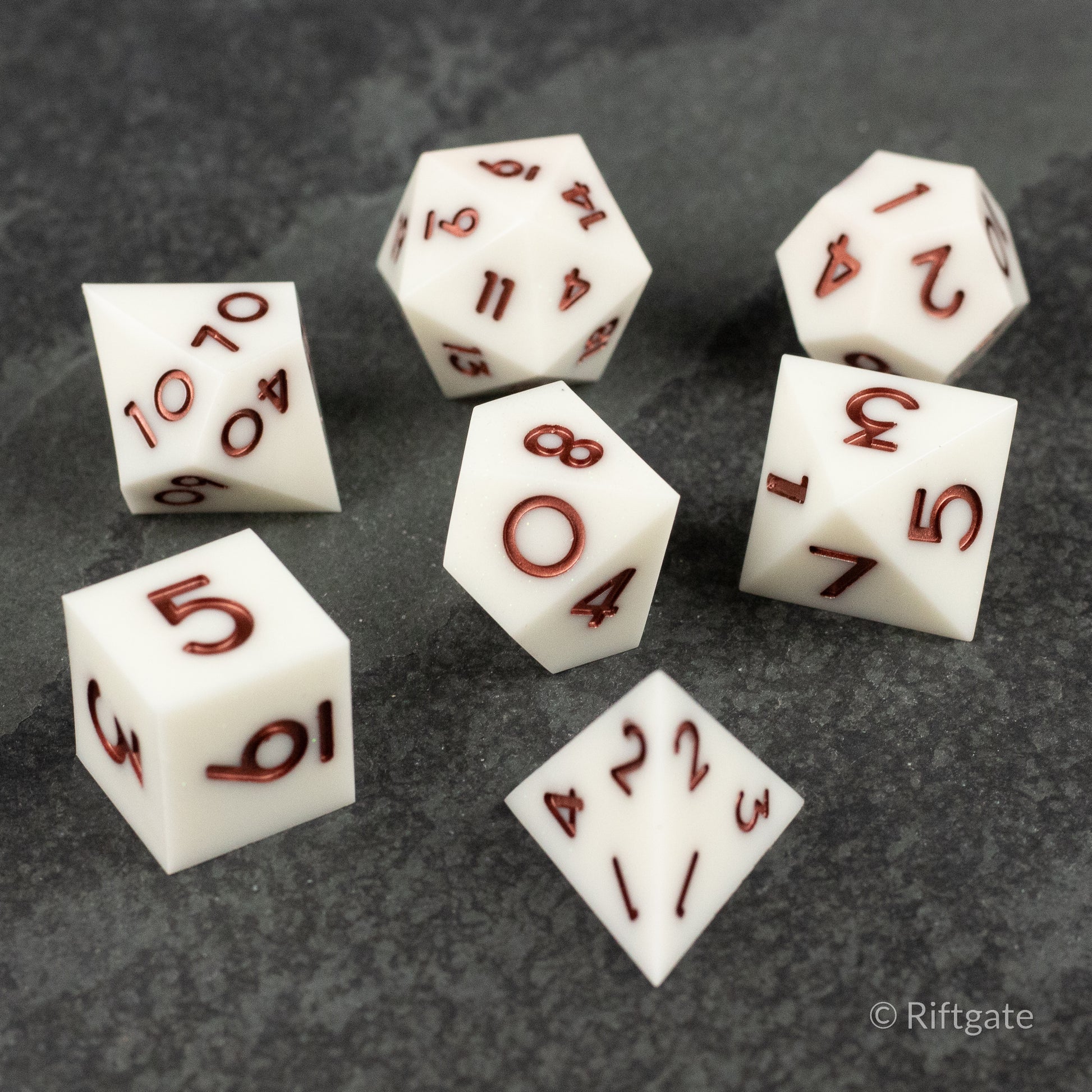 Glacial Spark Dice Set - Seven white polyhedral dice with sharp edges and deep red numbers, made for tabletop games.