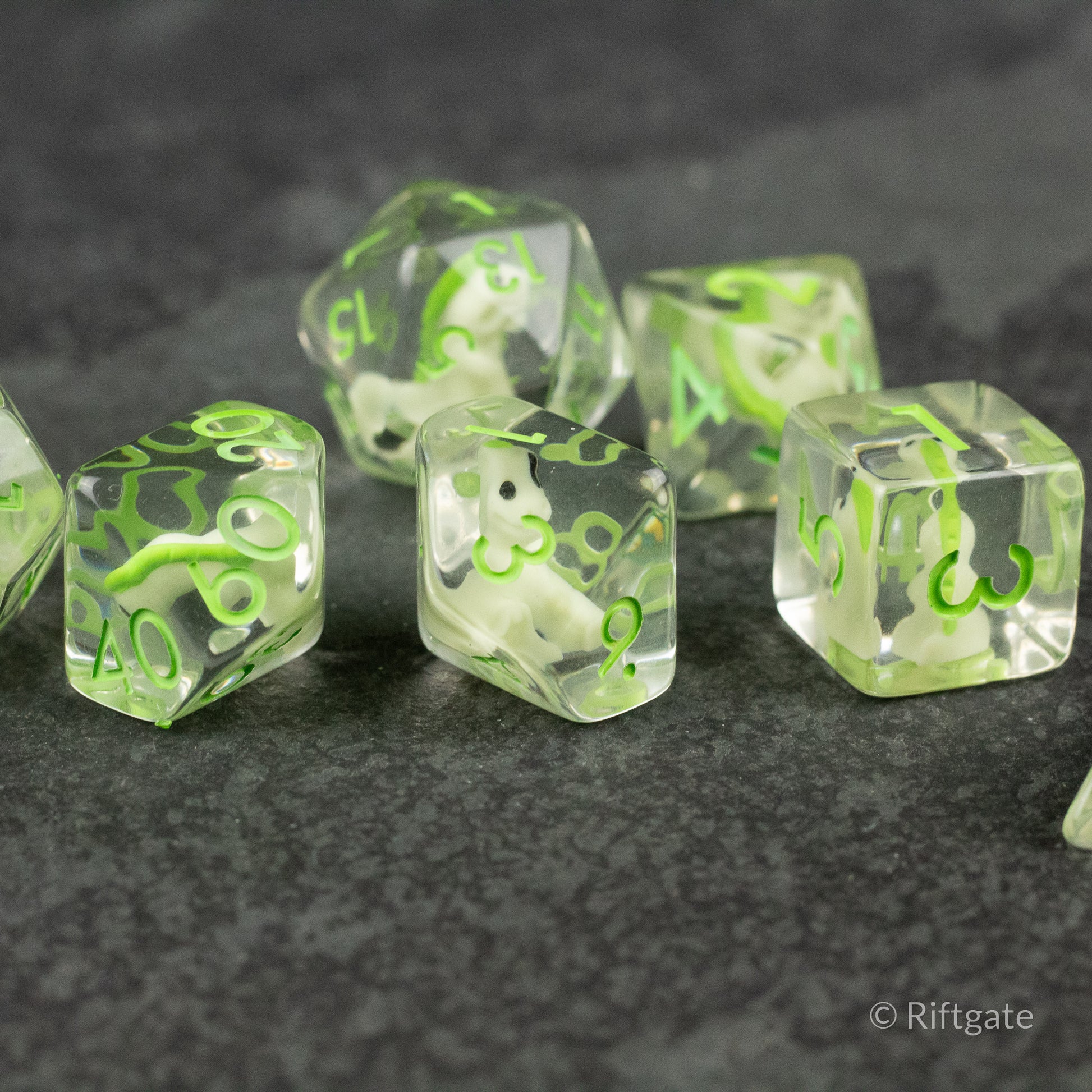 Green T-Rex Dice Set - Set of translucent clear dice with bright green T-Rex skull and bone patterns inside, six-sided shapes on dark surface.