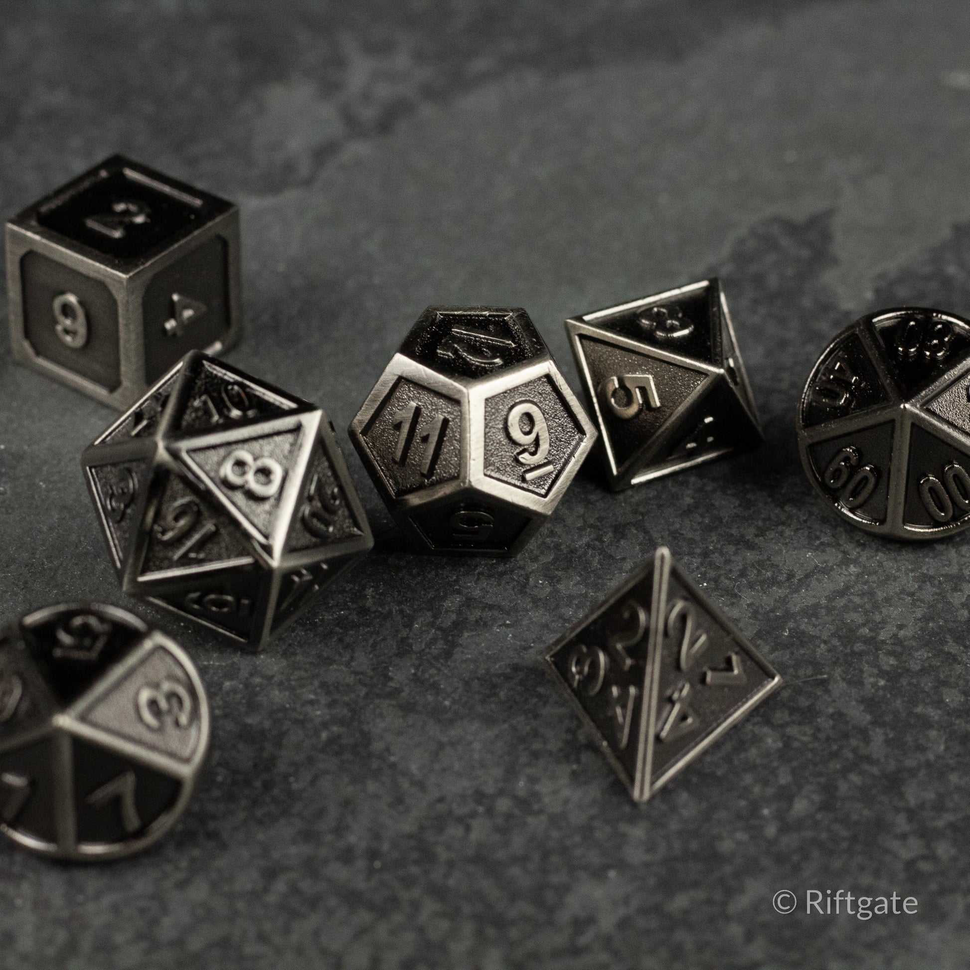 Shadowsteel Dice Set - Black metal polyhedral dice set with silver engraved numbers including d20, d12, d10, d8, d6, d4, and percentile dice.