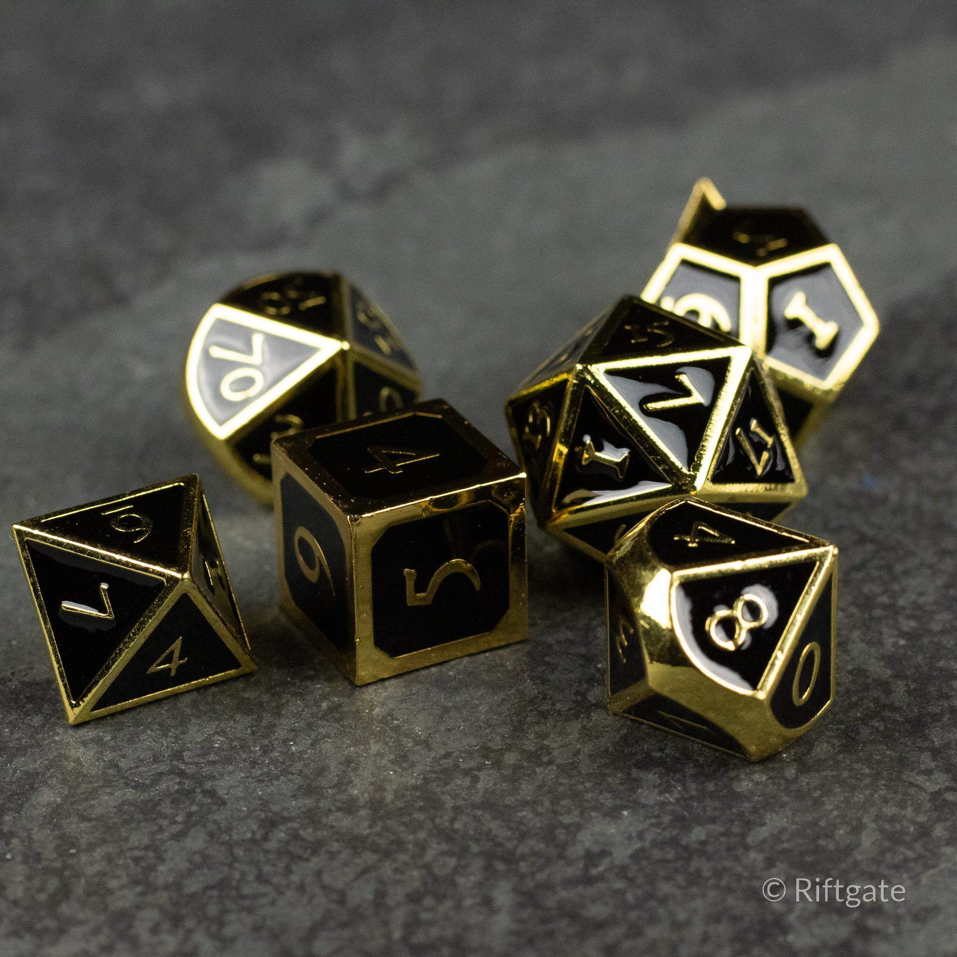 Aurum Eclipse Dice Set - Black metal polyhedral dice set with gold edges and numerals, including d4, d6, d8, d10, d12, and d20 shapes.