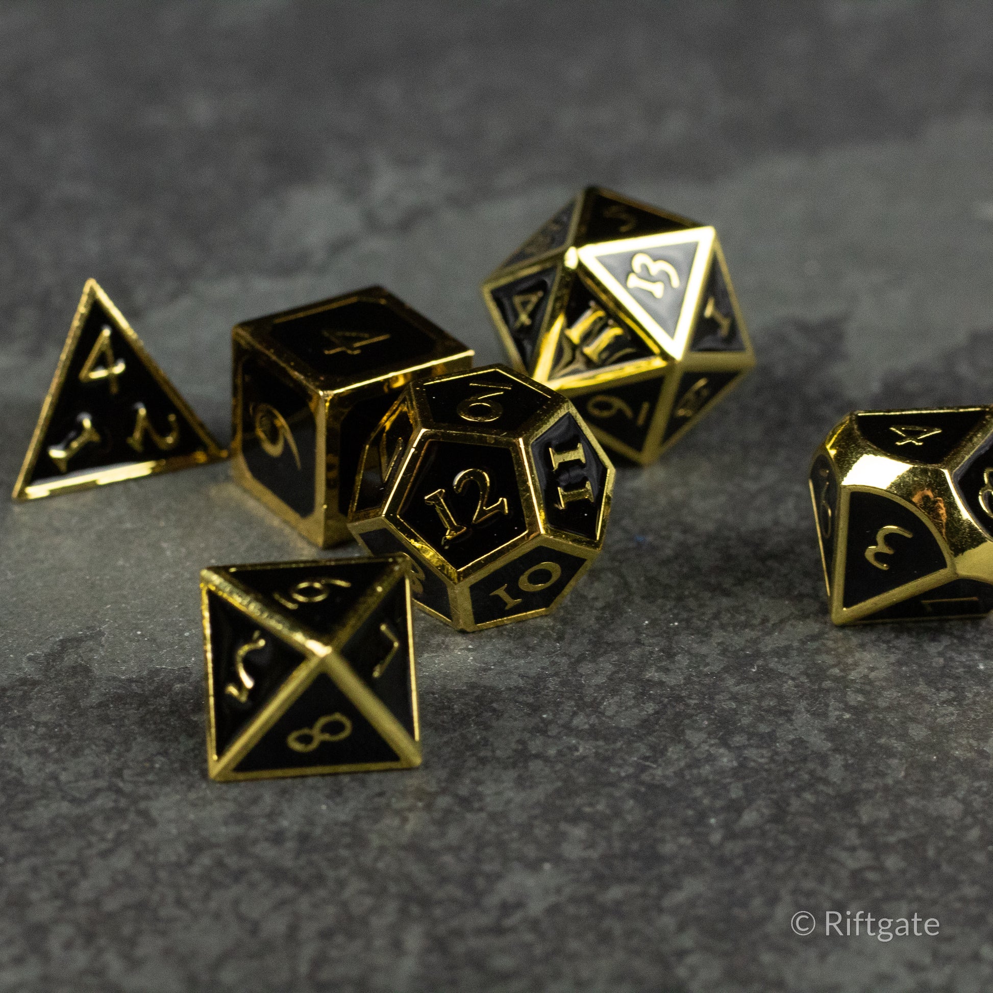 Aurum Eclipse Dice Set - Black metal polyhedral dice set with gold numbering and edges, including d4, d6, d8, d10, d12, and d20 shapes.