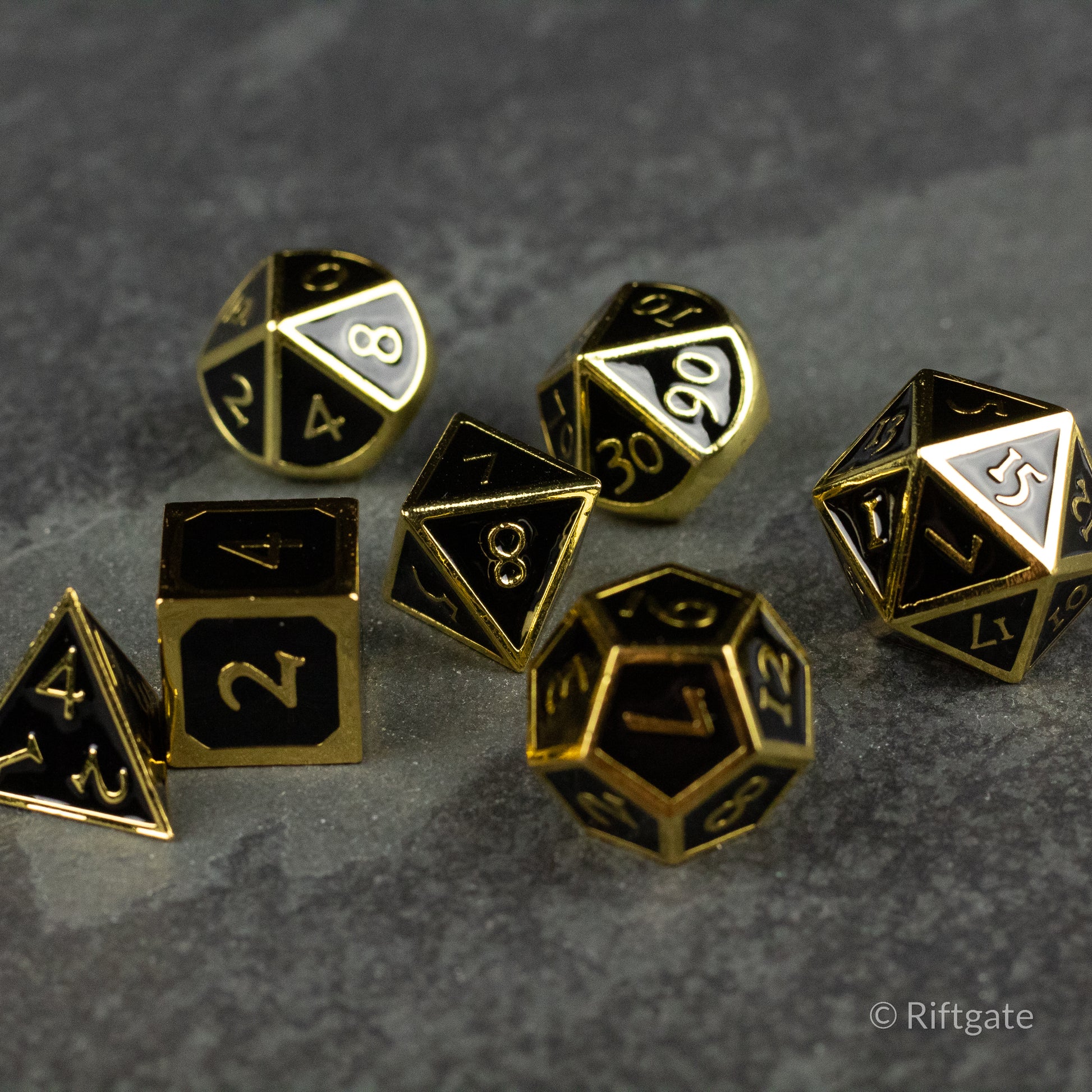Aurum Eclipse Dice Set - Black metal polyhedral dice set with gold edges and white numbering, featuring various shapes including D20, D12, D10, D8,.