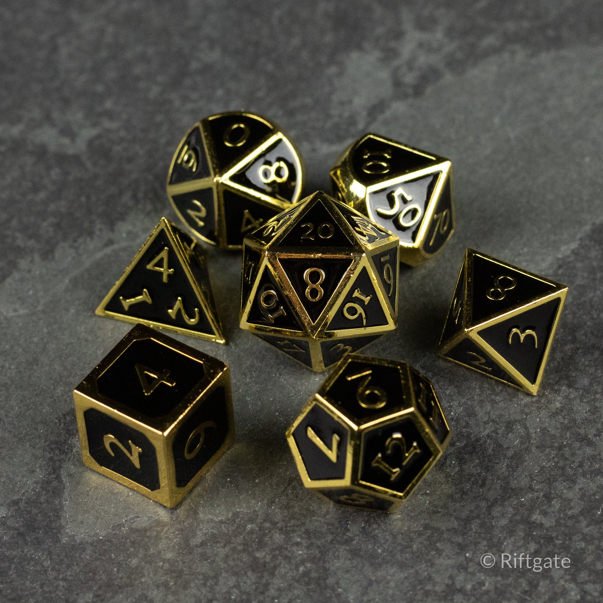 Aurum Eclipse Dice Set - Seven-piece metal dice set in black finish with gold edges and engraved numbers, including d4, d6, d8, d10, d12, and d20.