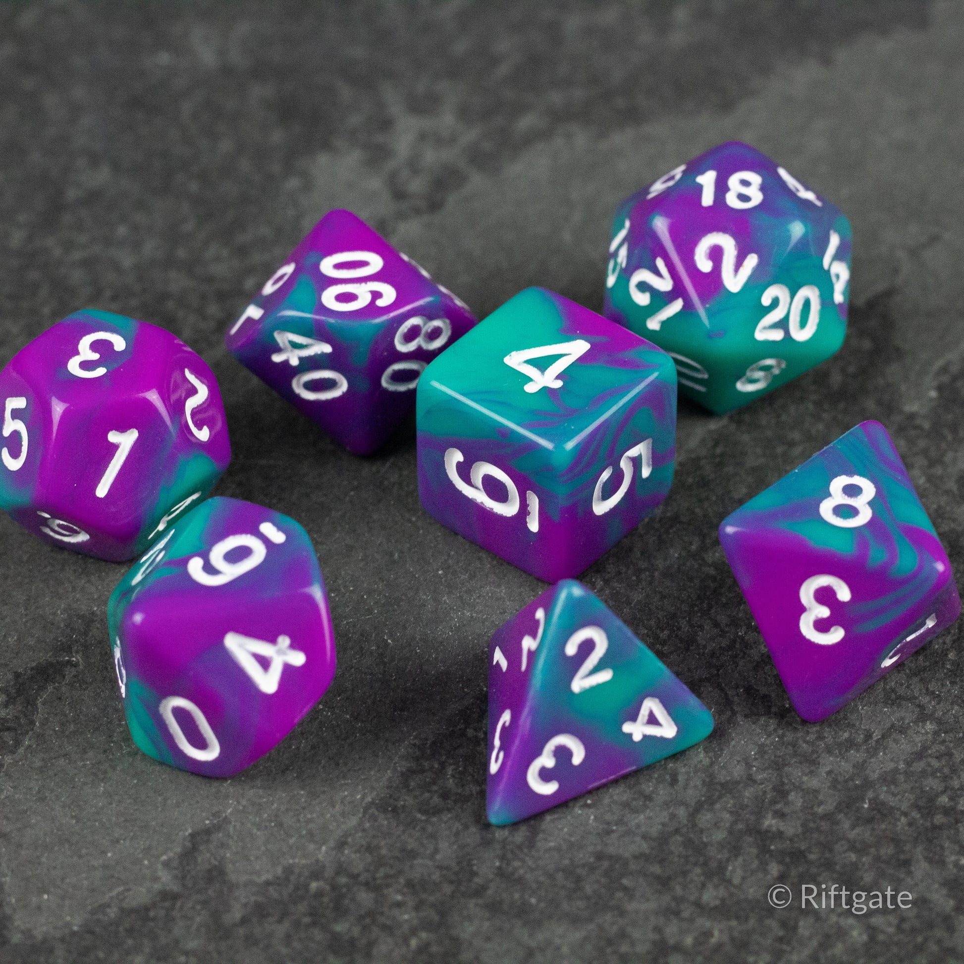 Purple and Turquoise Marbled Dice Set - Purple and turquoise marbled seven-piece dice set with white numbers on a gray surface.