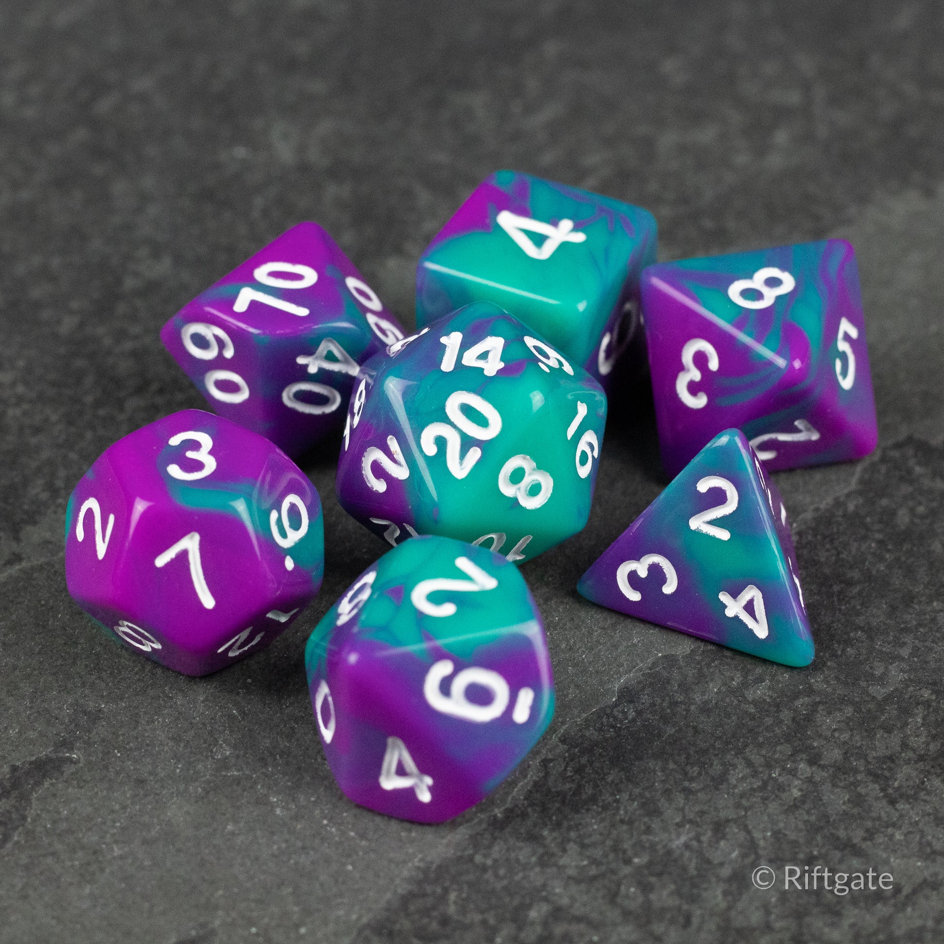 Purple and Turquoise Marbled Dice Set - Seven purple and turquoise marbled polyhedral dice with white numbers on a dark stone surface.