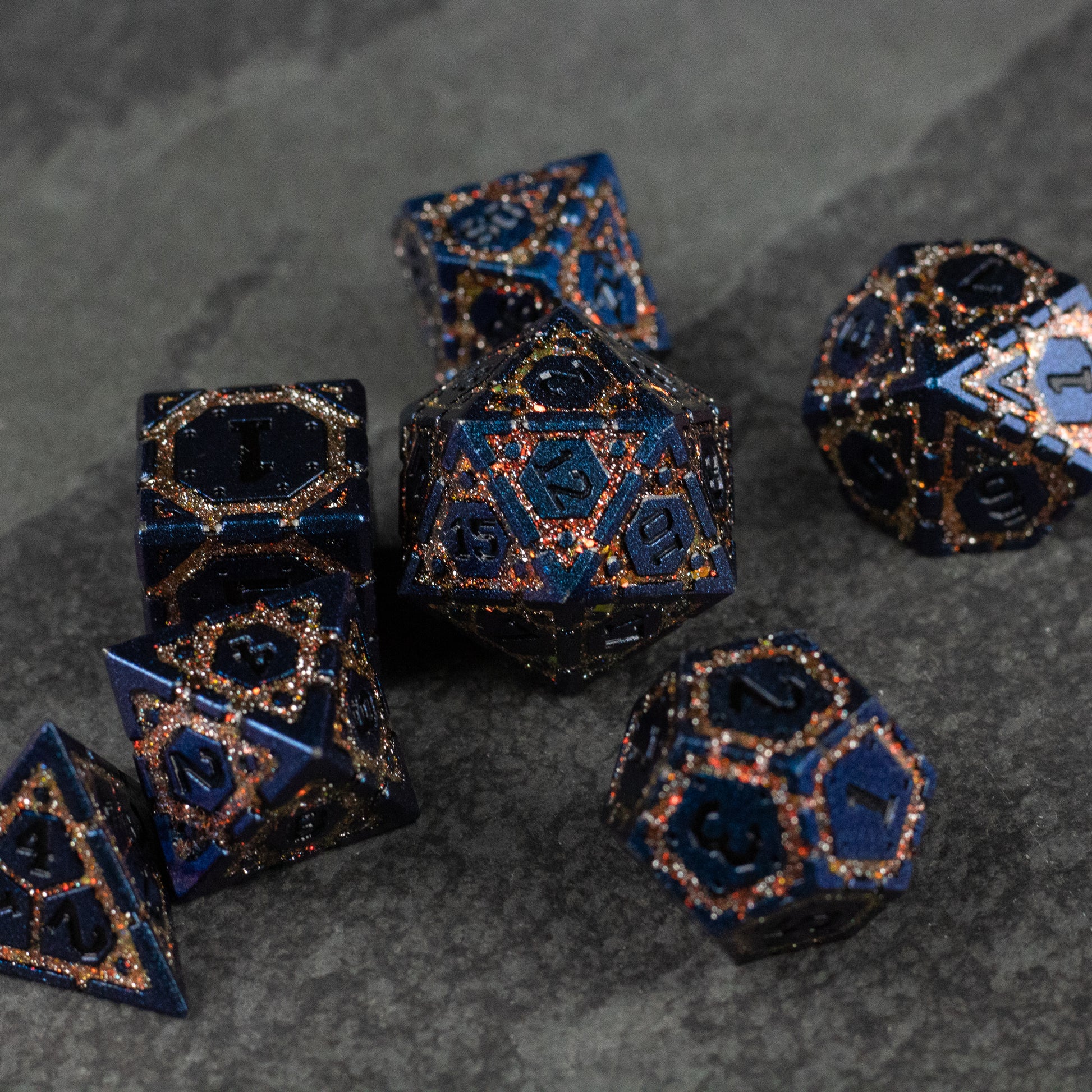 Gold Superior Ward Metal Dice Set - Black metal polyhedral dice set with gold intricate filigree patterns on dark stone surface.