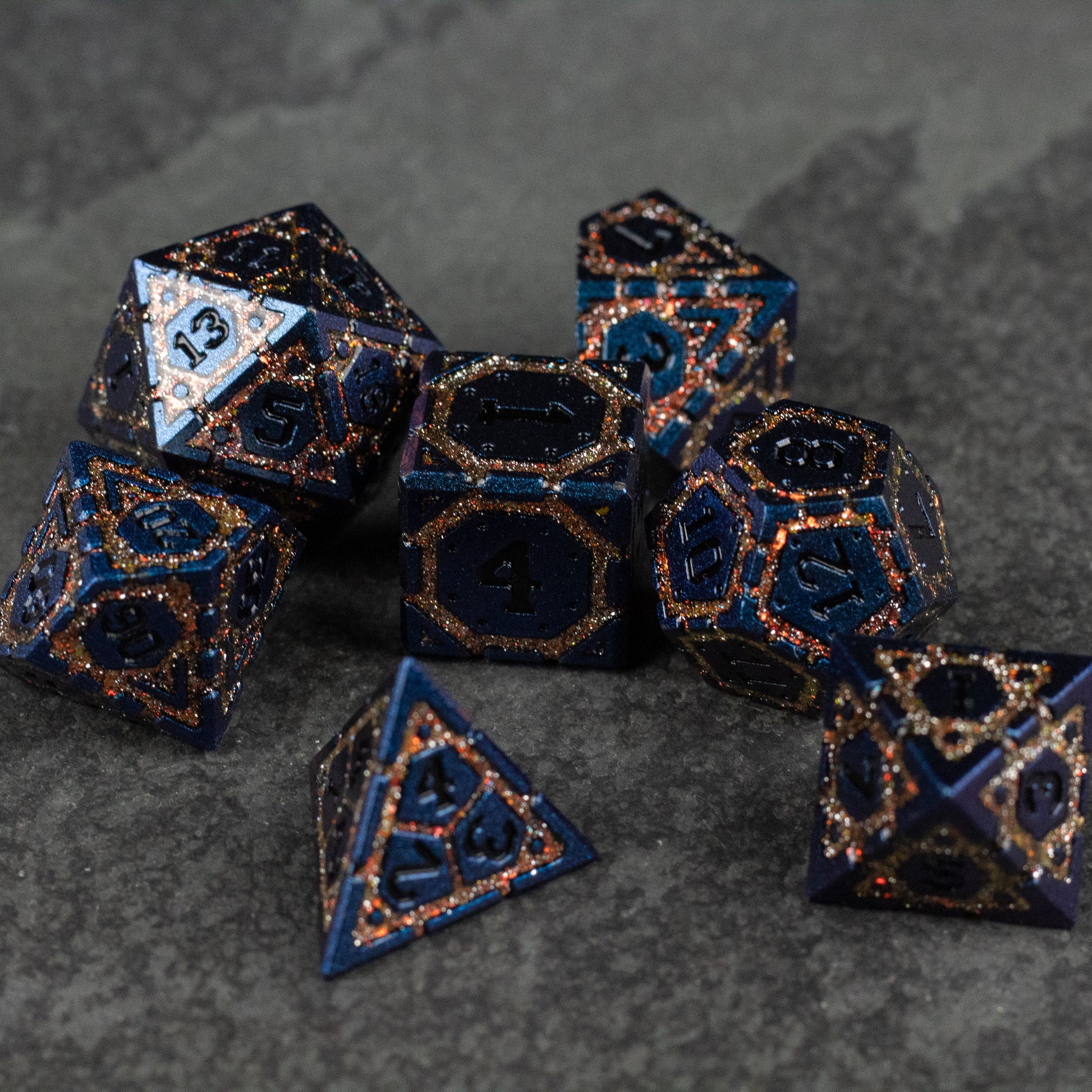 Gold Superior Ward Metal Dice Set - Set of seven dark blue metal dice with gold numbering and intricate gold patterns, featuring various polygon shapes for.