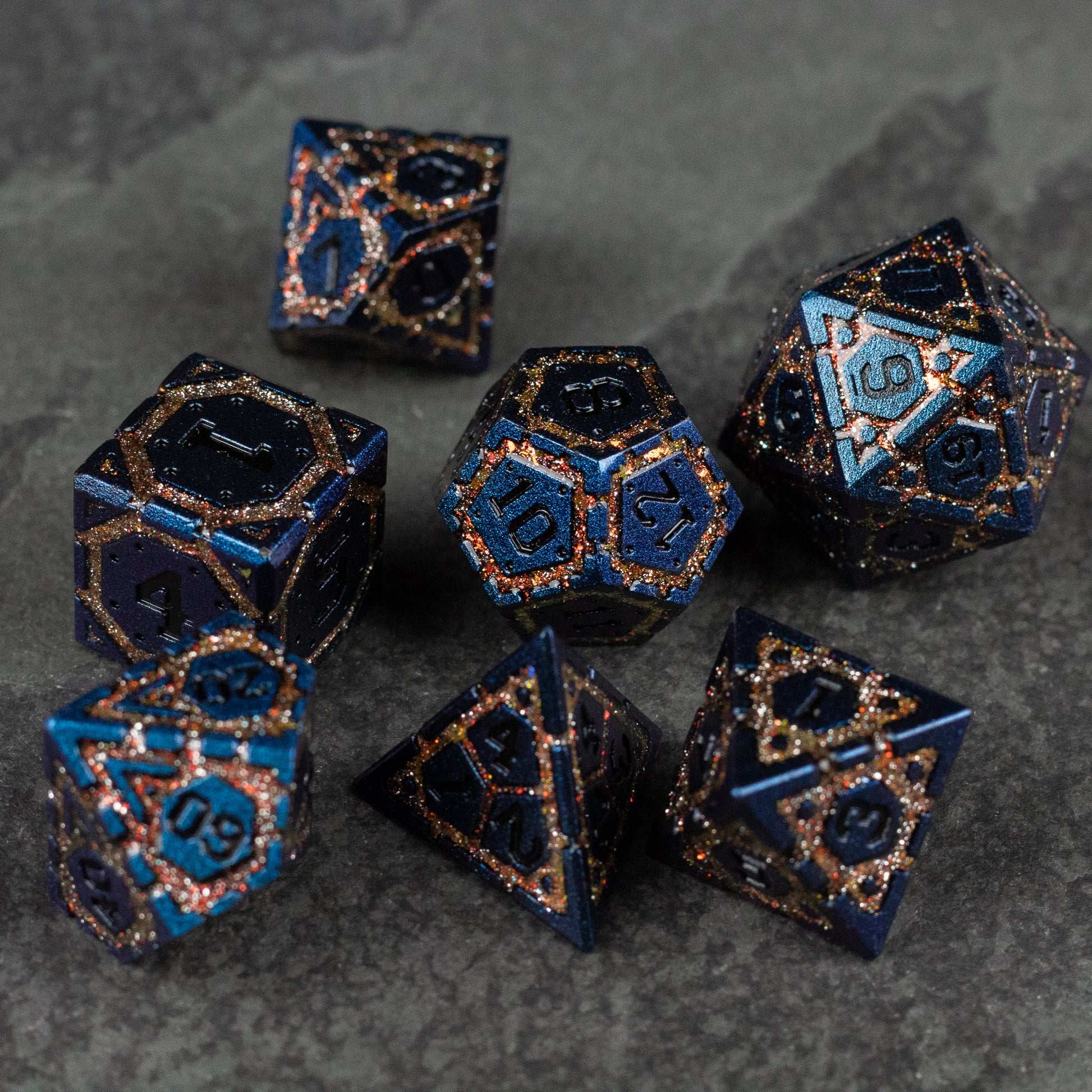 Gold Superior Ward Metal Dice Set - Set of seven dark blue metal polyhedral dice with gold speckles and gold etched numbers.